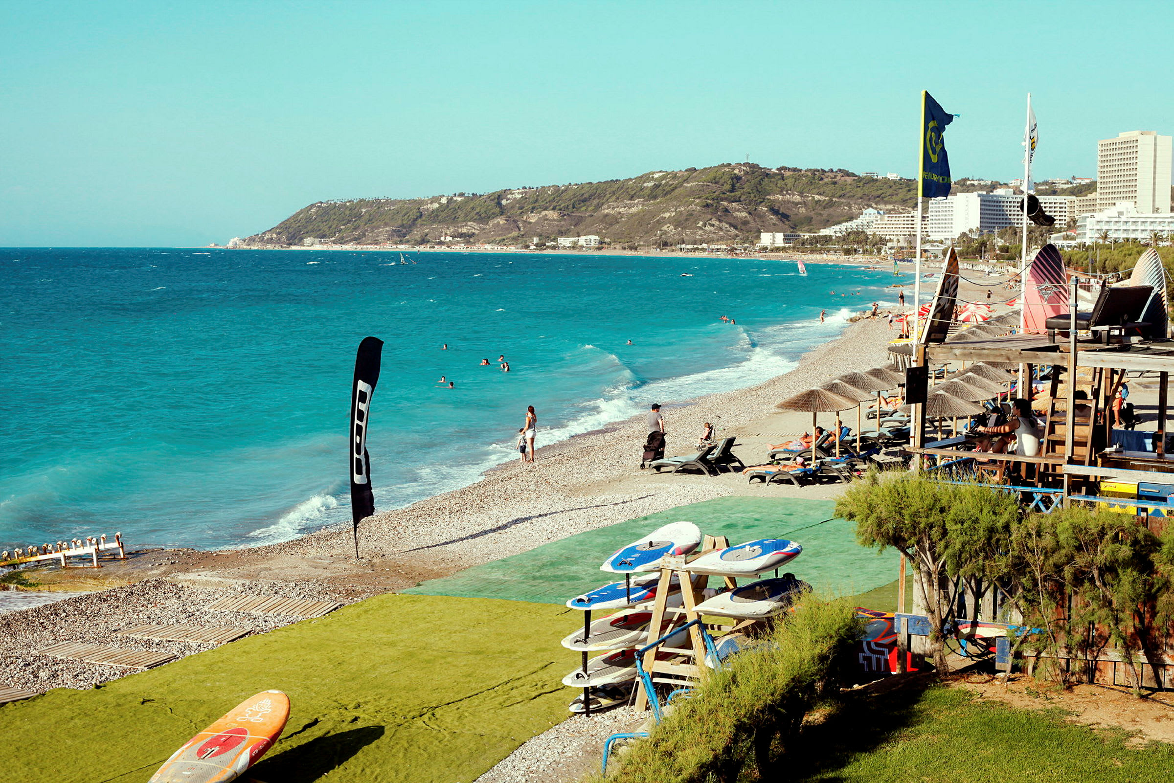 Strand vid havet med solstolar och surfingbrädor vid sidan. (AI-genererad text)