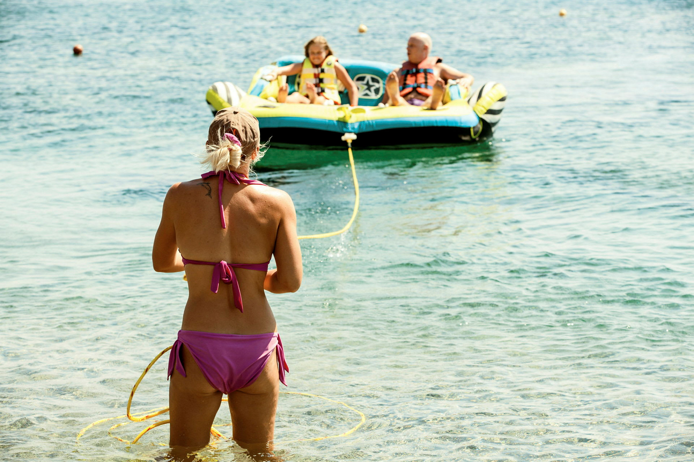 En person står i vatten och håller i ett gult rep som leder till en uppblåsbar båt på havet. (AI-genererad text)