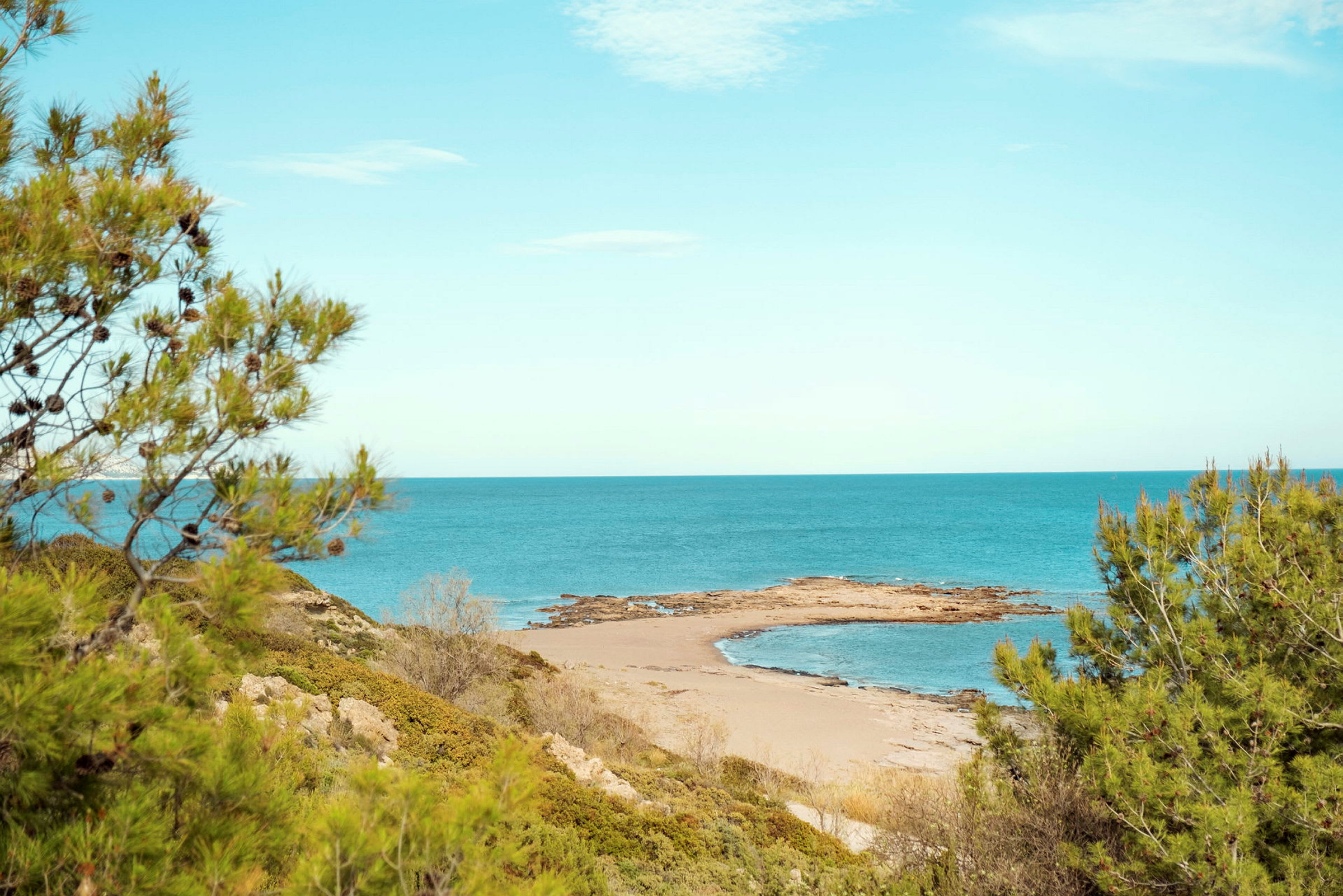 En avlägsen sandstrand med omgivande vegetation och havet i bakgrunden. (AI-genererad text)