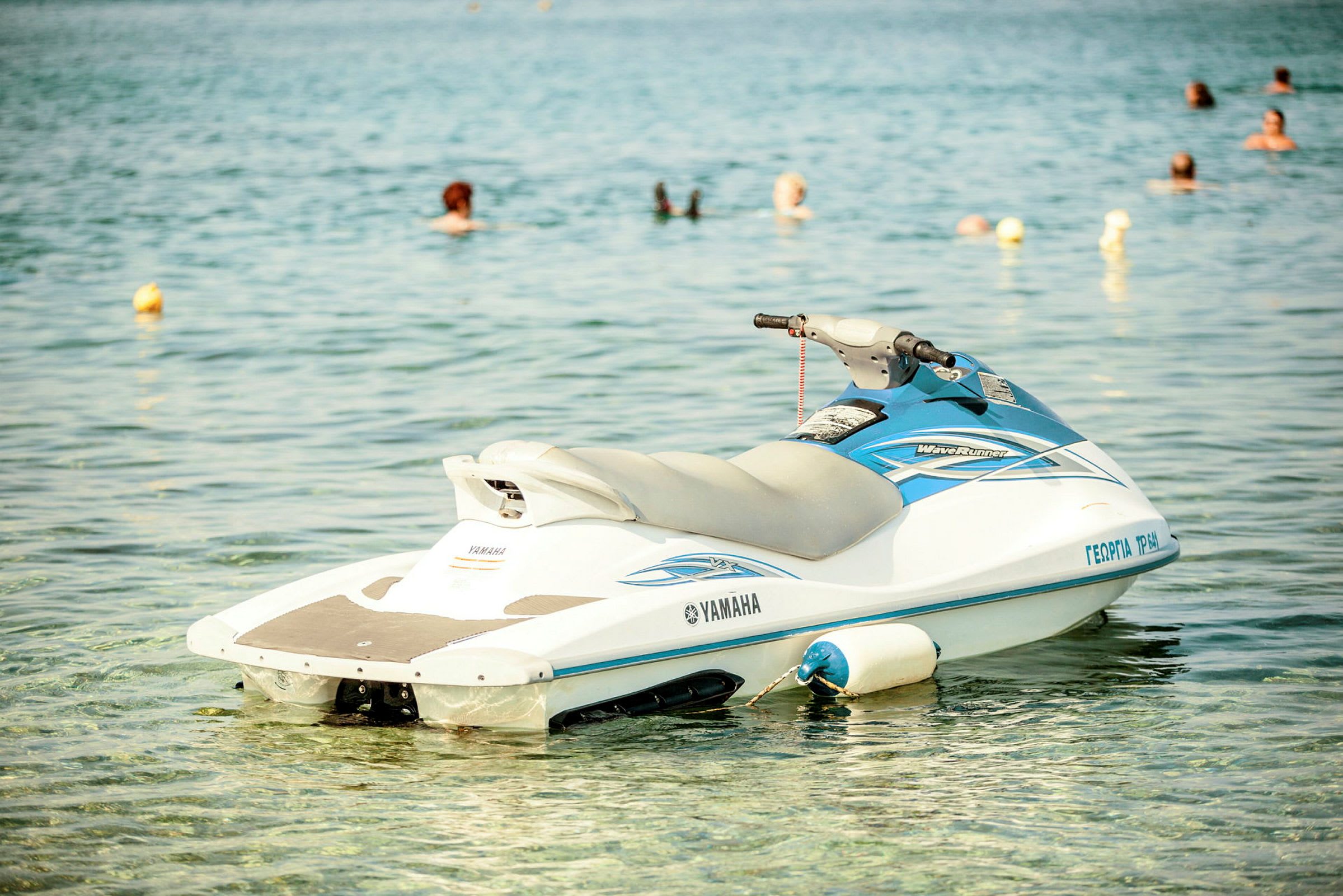 En jetski flyter på vatten med simmande personer i bakgrunden. (AI-genererad text)