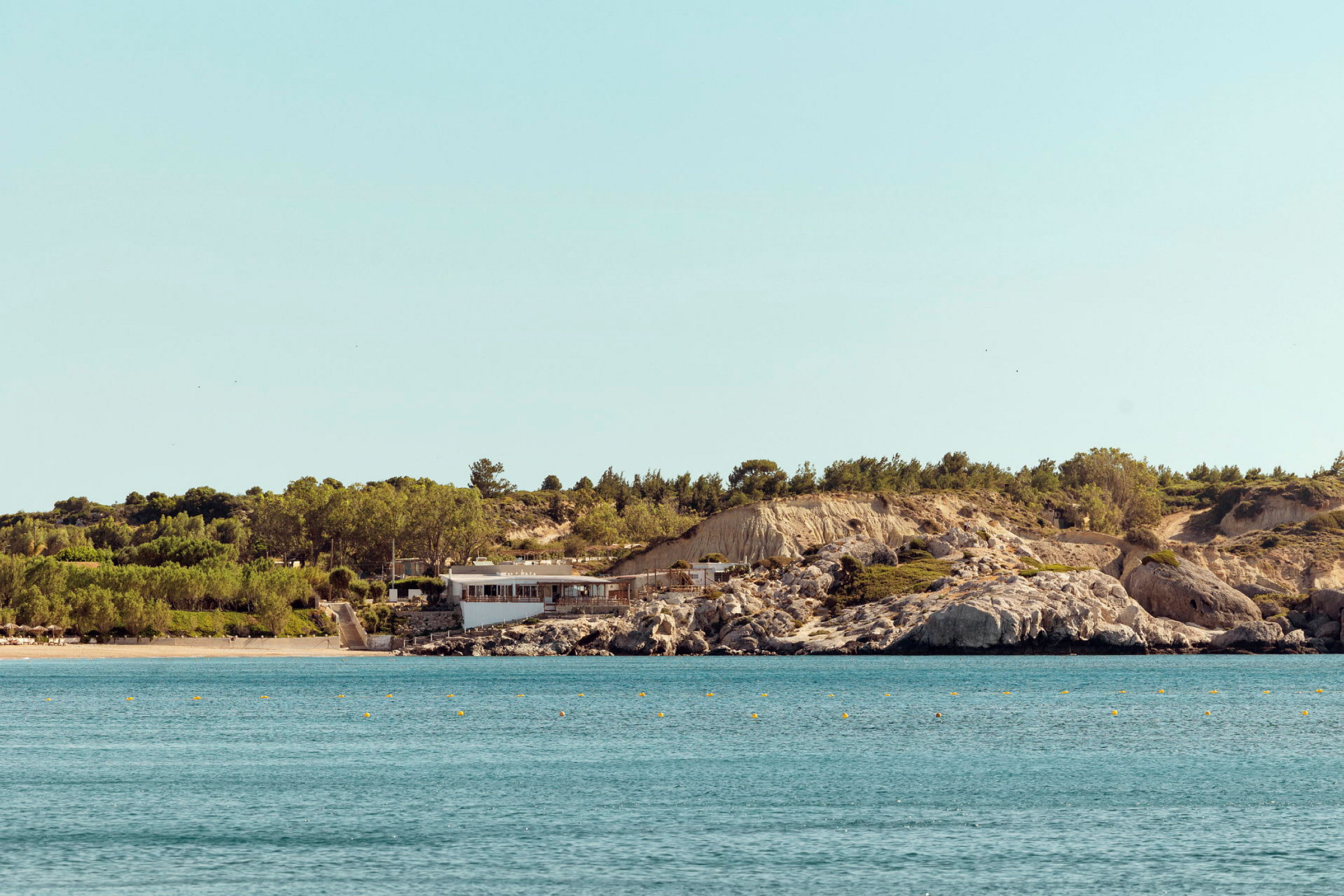 En strand och ett hav med en byggnad vid en klippig kust. (AI-genererad text)