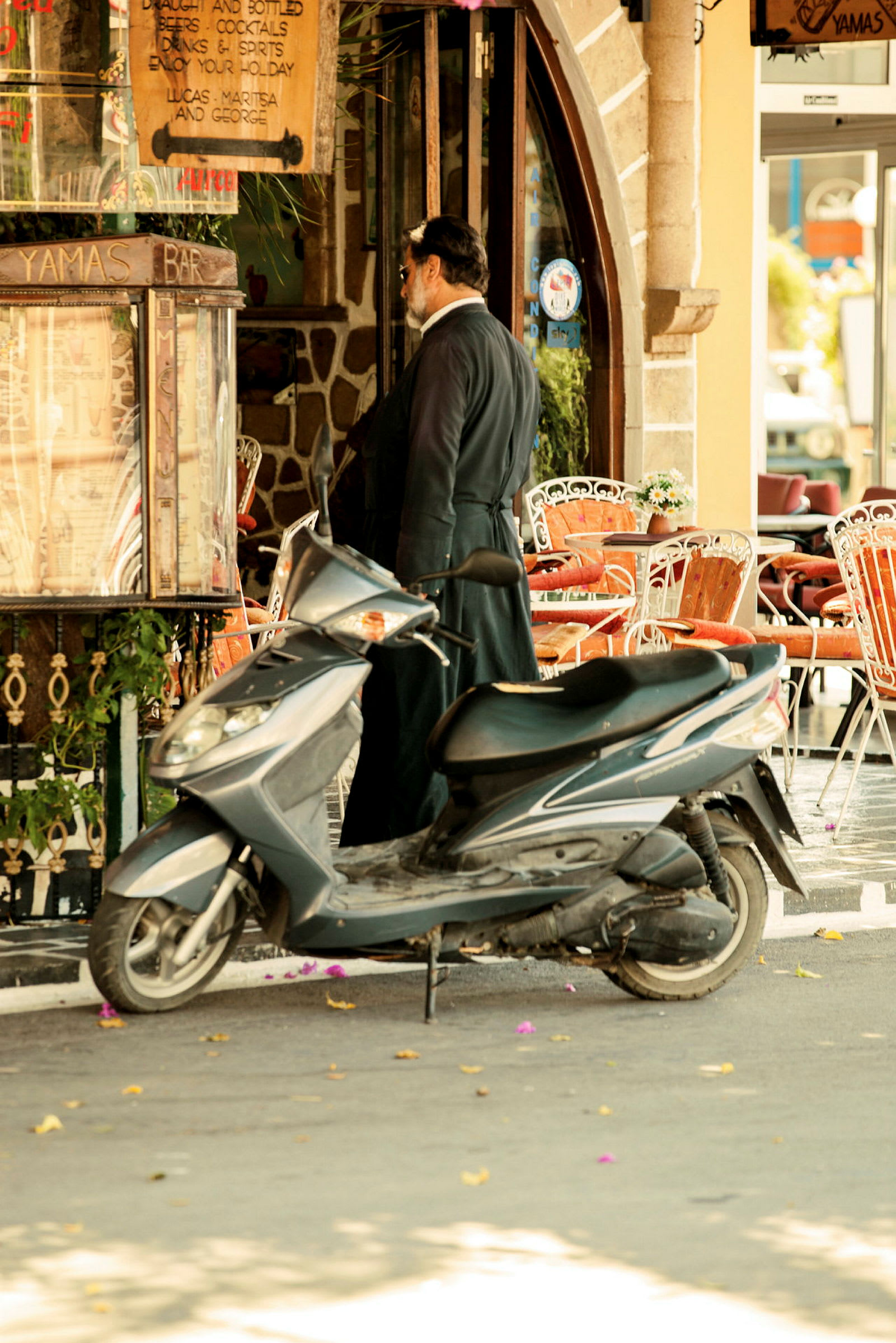 En motorcykel parkerad nära en restaurang med uteservering. (AI-genererad text)