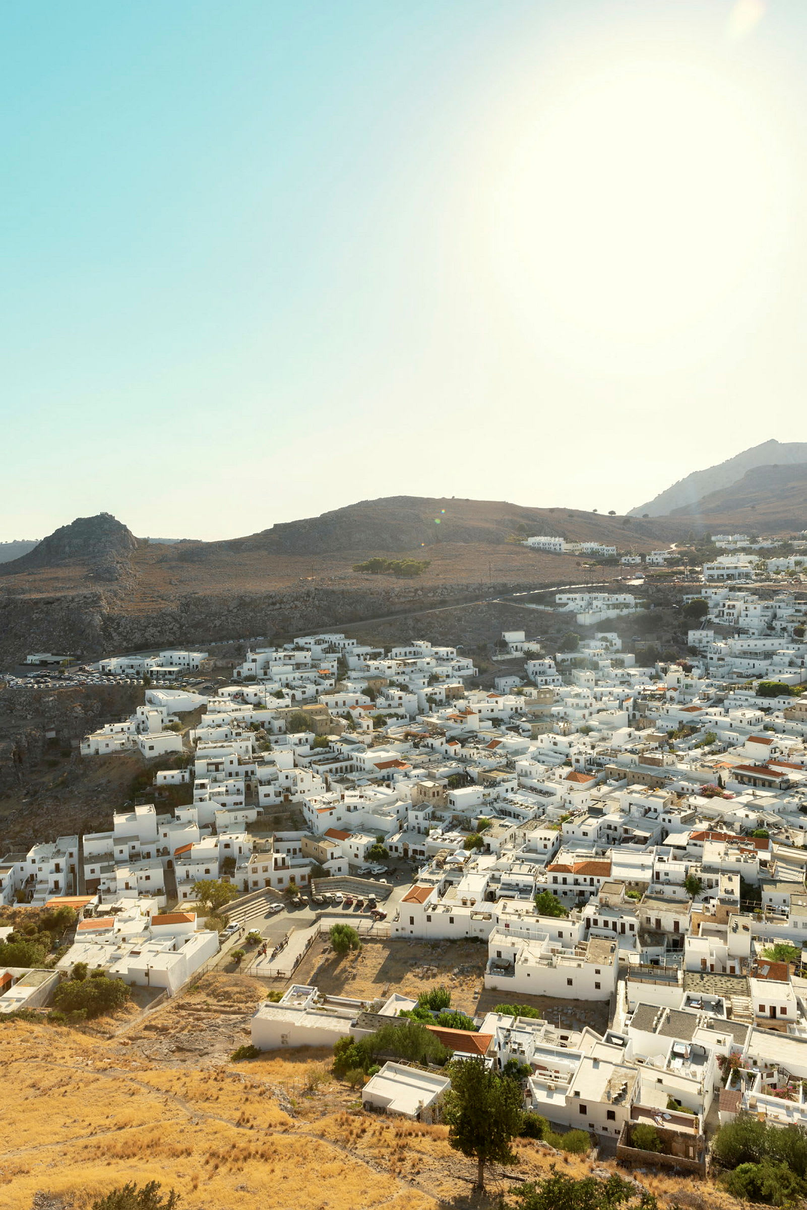 Ett solbelyst landskap med en tät samling av vita hus på en kulle och omgivna av torra berg och stäpp. (AI-genererad text)
