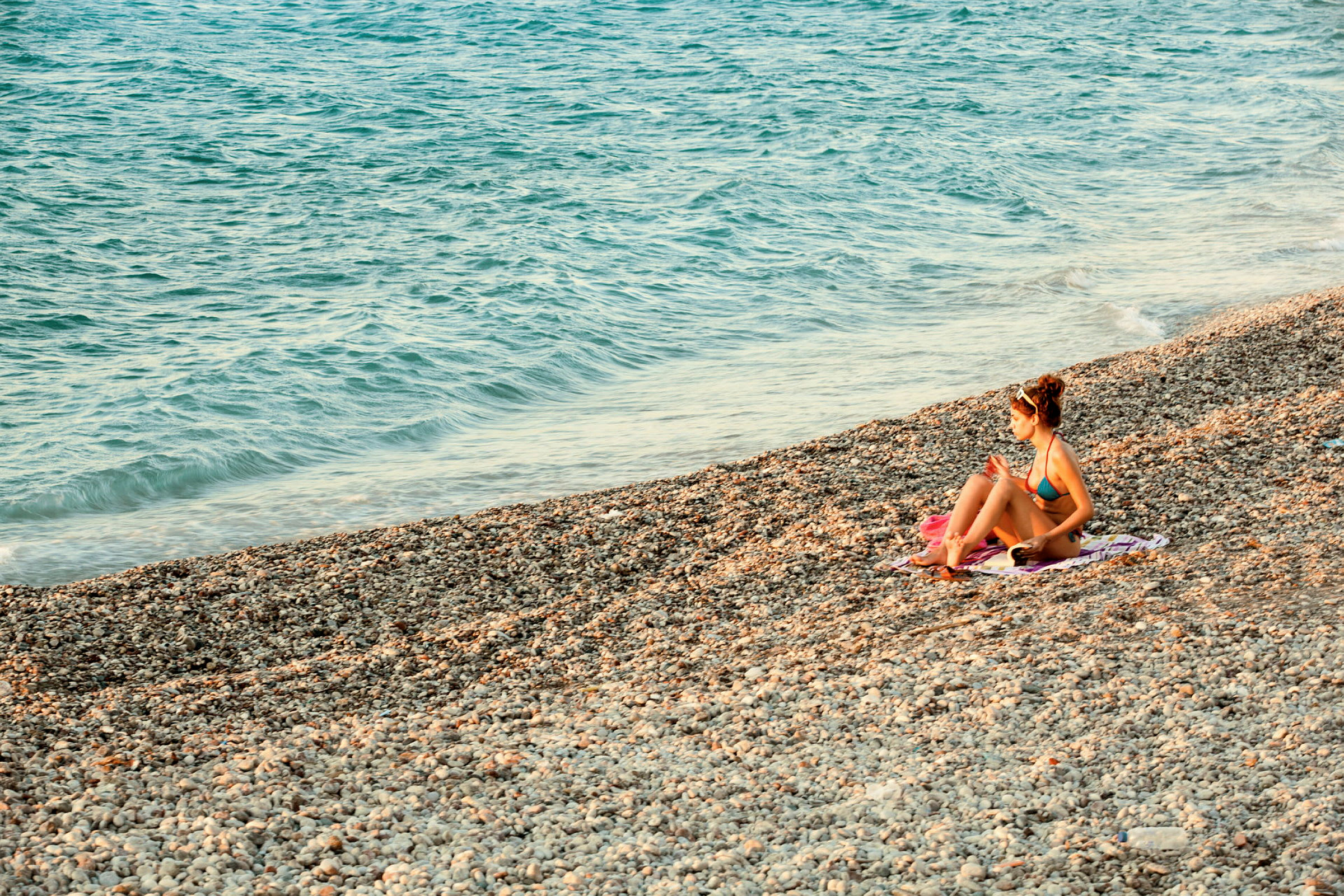 Person sitter på en stenstrand nära havet. (AI-genererad text)