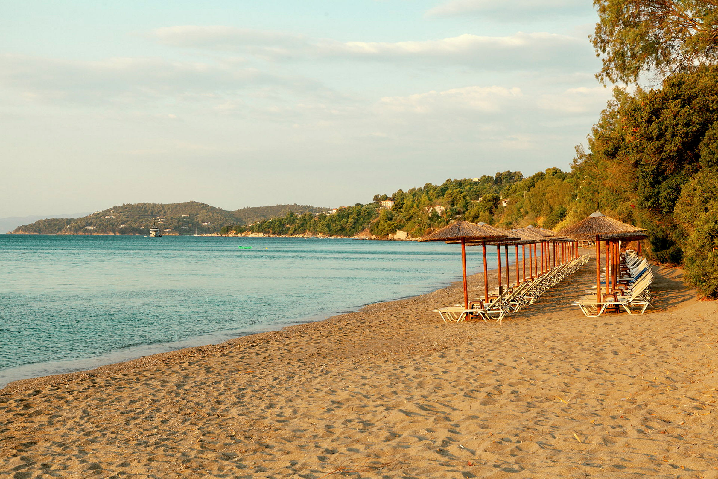 Strand med parasoller och solstolar vid havet. (AI-genererad text)