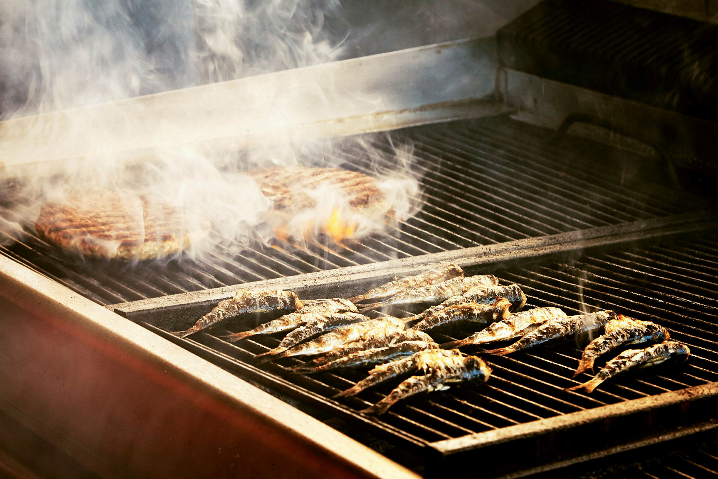 Fiskar och kött som grillas på en grill. (AI-genererad text)