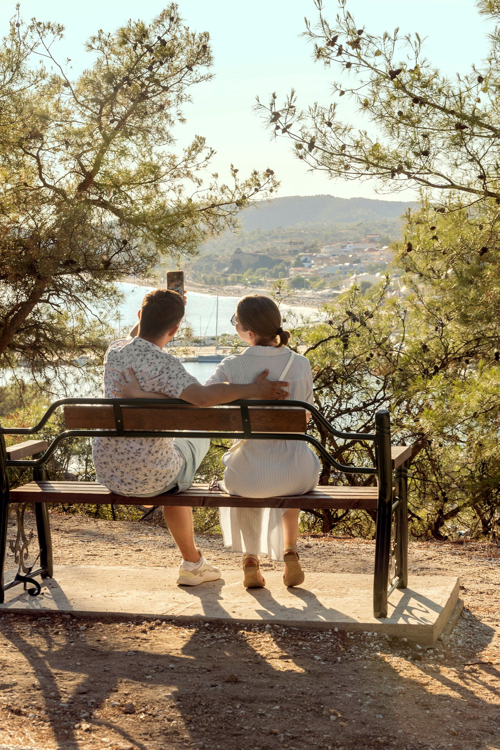 Två personer sitter på en bänk med utsikt över en hamn. (AI-genererad text)