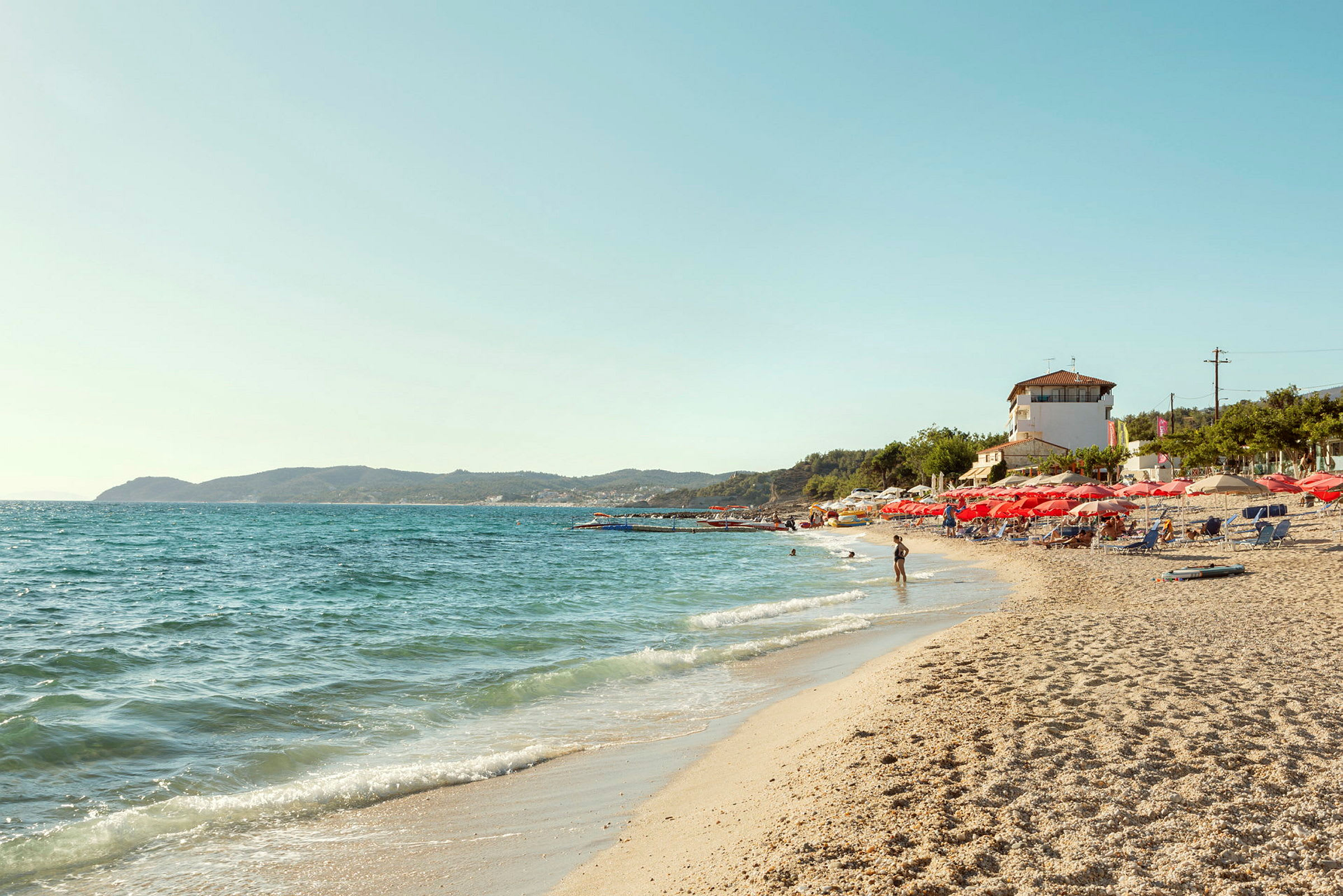Strand med solstolar och parasoll vid havet. (AI-genererad text)