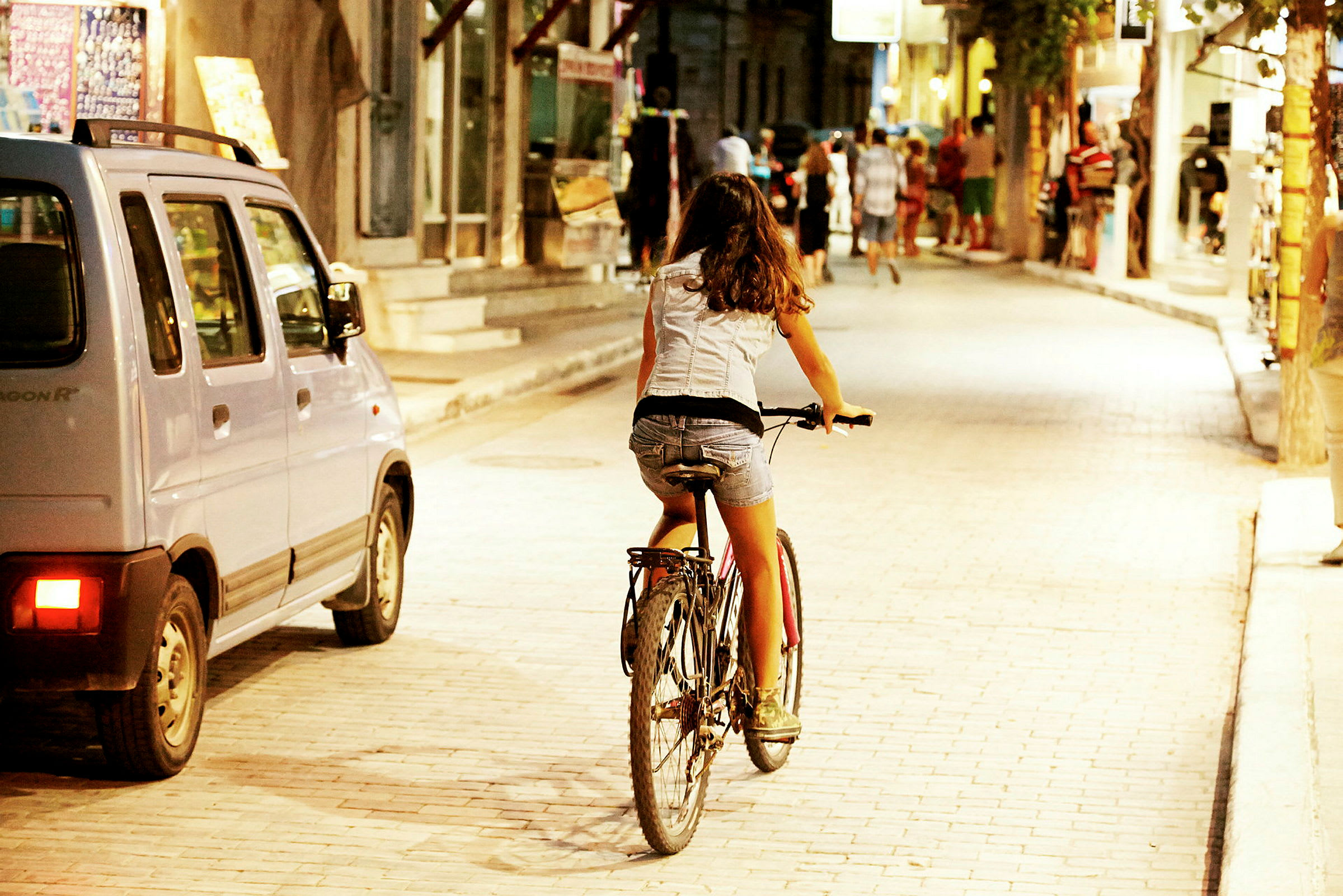 Person cyklar på en gata med butiker och människor. (AI-genererad text)
