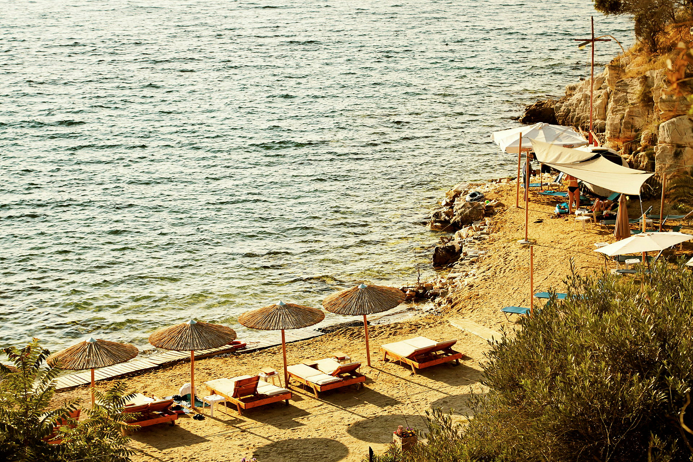 Strand med solstolar, parasoller och klart hav. (AI-genererad text)
