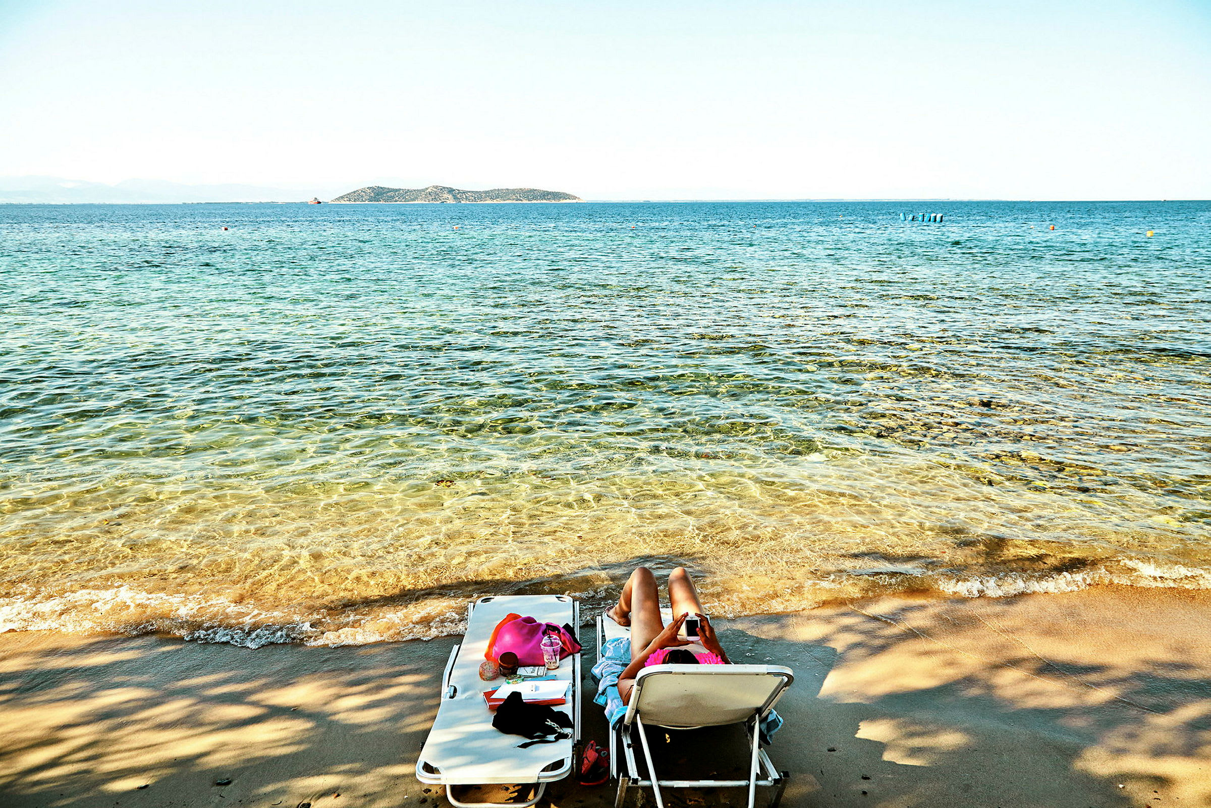 Person ligger på en solstol vid stranden med havet i bakgrunden. (AI-genererad text)