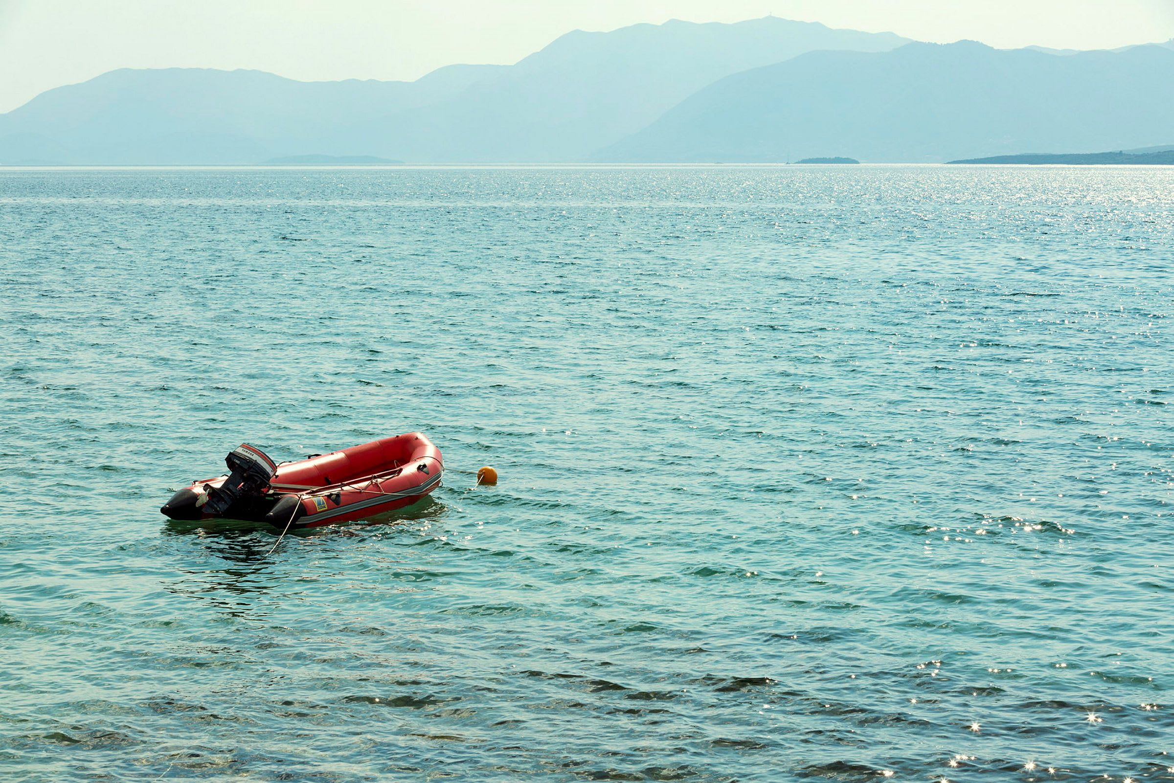 En röd gummibåt ligger förtöjd vid en boj i havet. (AI-genererad text)