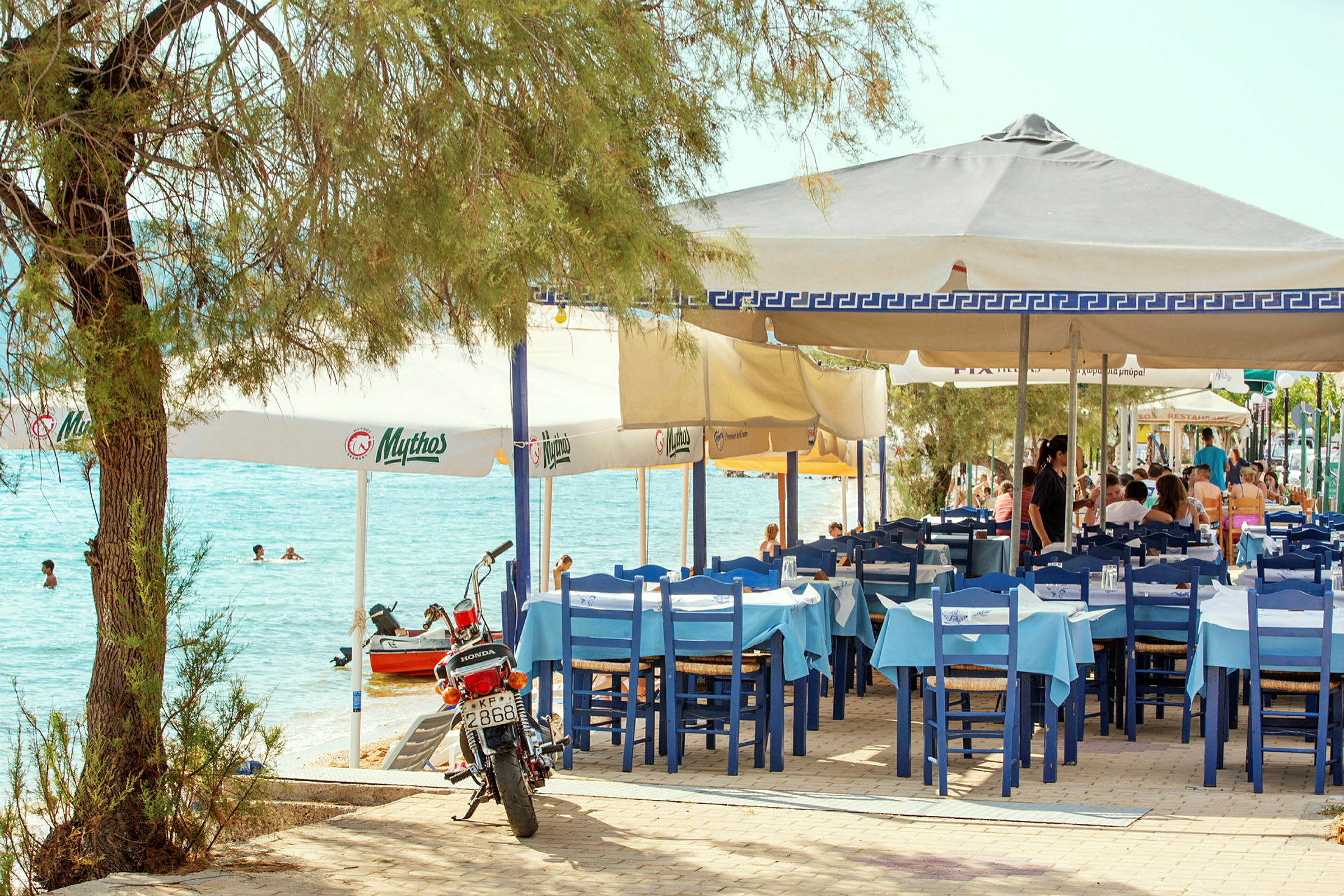 Restaurang med blå och vita stolar vid havet. (AI-genererad text)