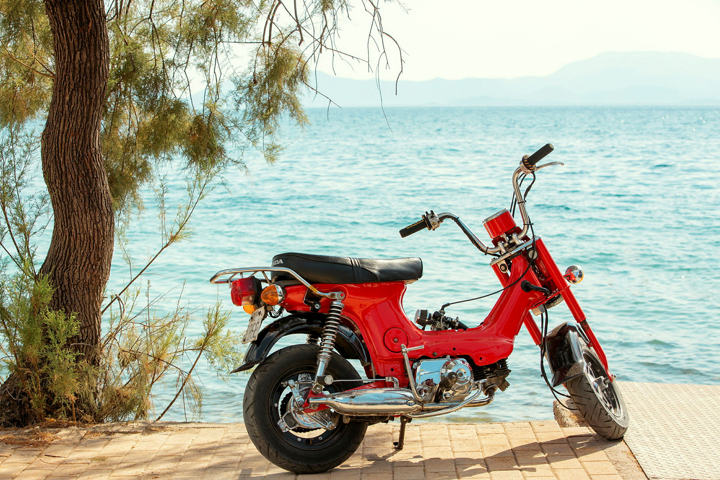 En röd motorcykel står parkerad vid havet. (AI-genererad text)
