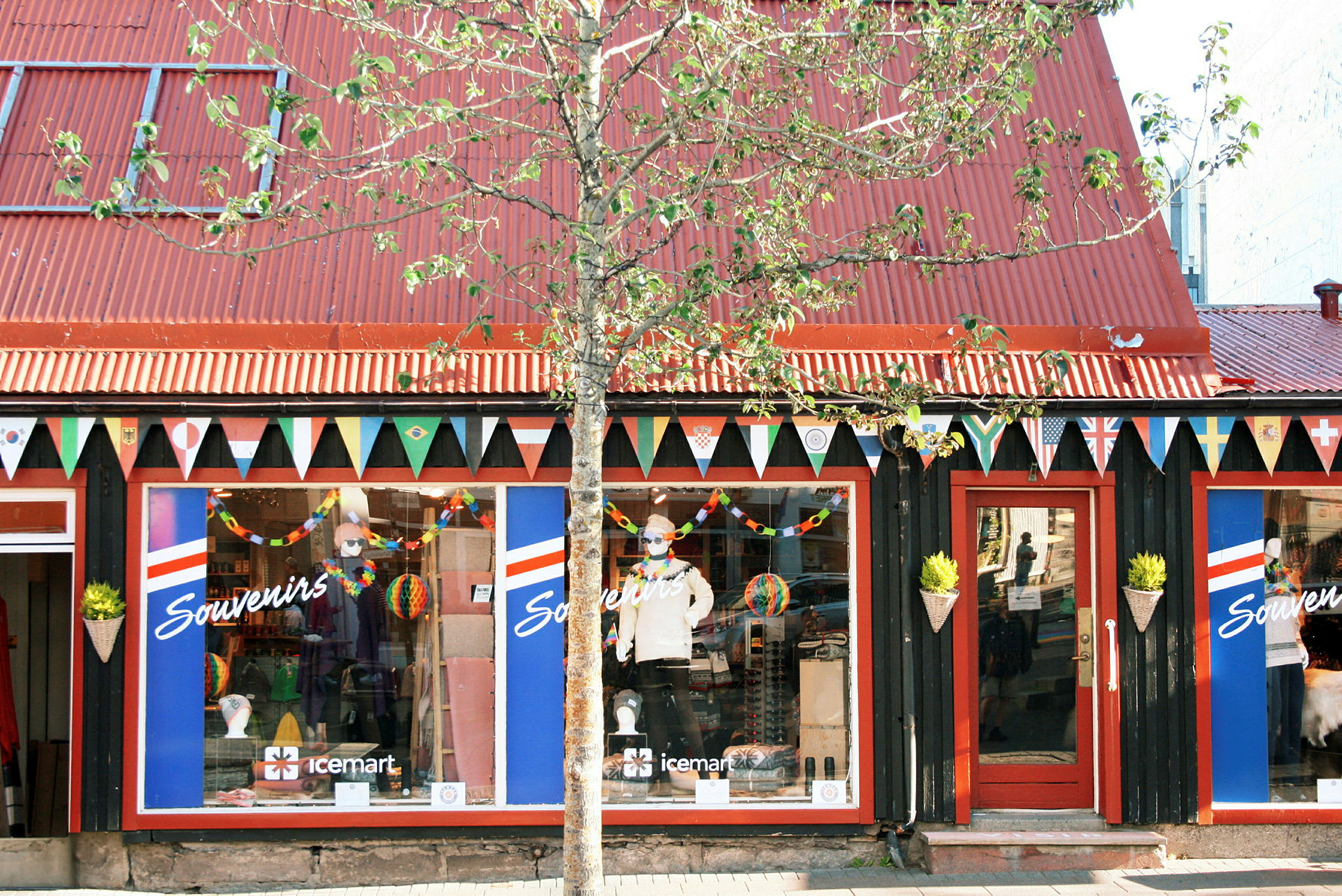 En souvenirbutik med rödfärgat tak och vimplar med nationsflaggor hängandes ovanför skyltfönstren. (AI-genererad text)