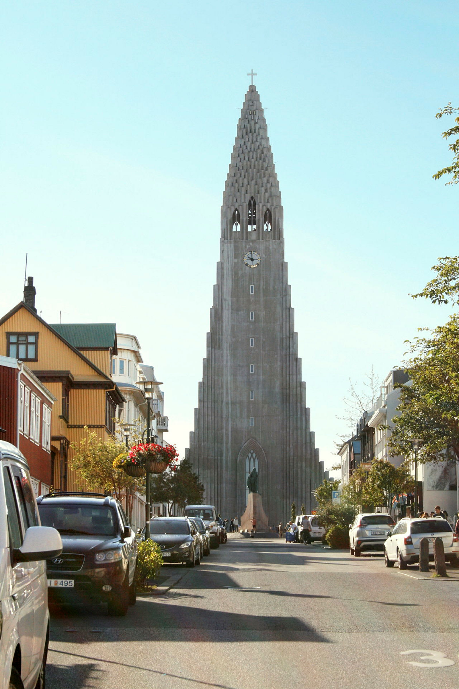 Ett foto av en gata med bilar parkerade på sidorna, och i bakgrunden syns en hög kyrka med en unik arkitektur. (AI-genererad text)