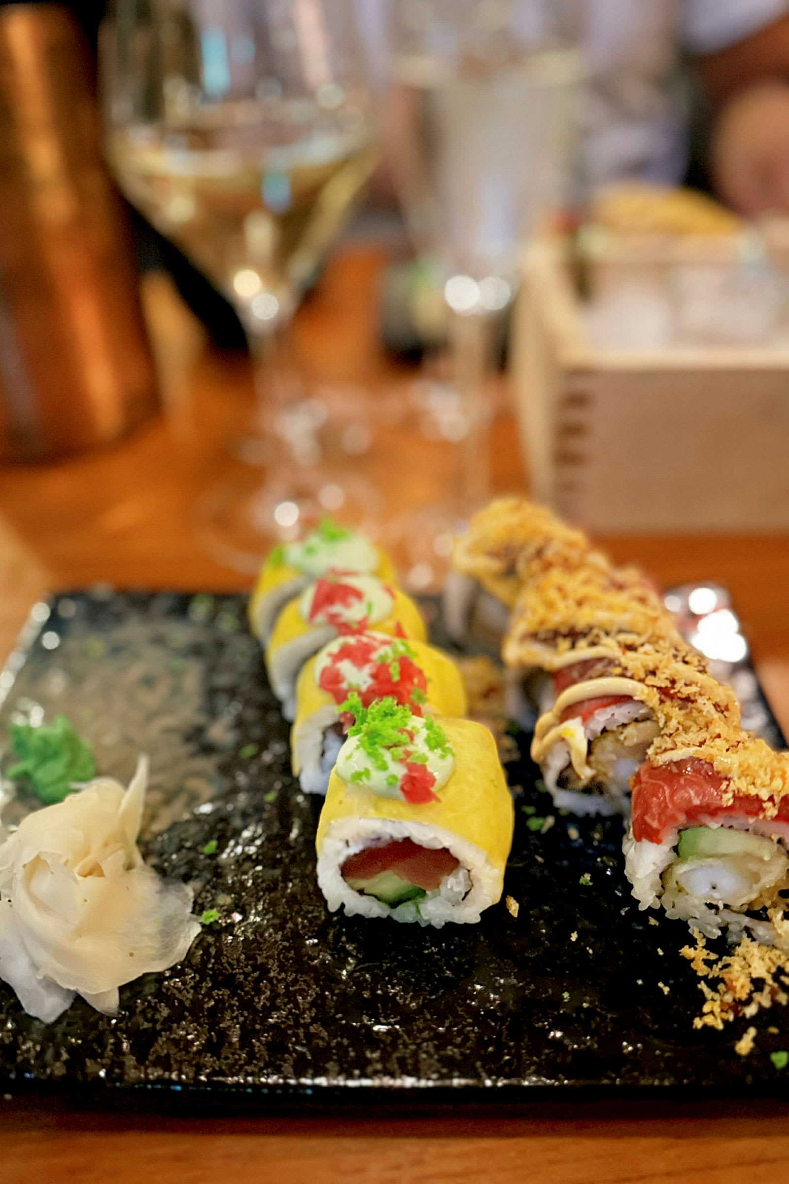 En tallrik med två rader sushi och tillbehör, serverad på ett mörkt fat. (AI-genererad text)