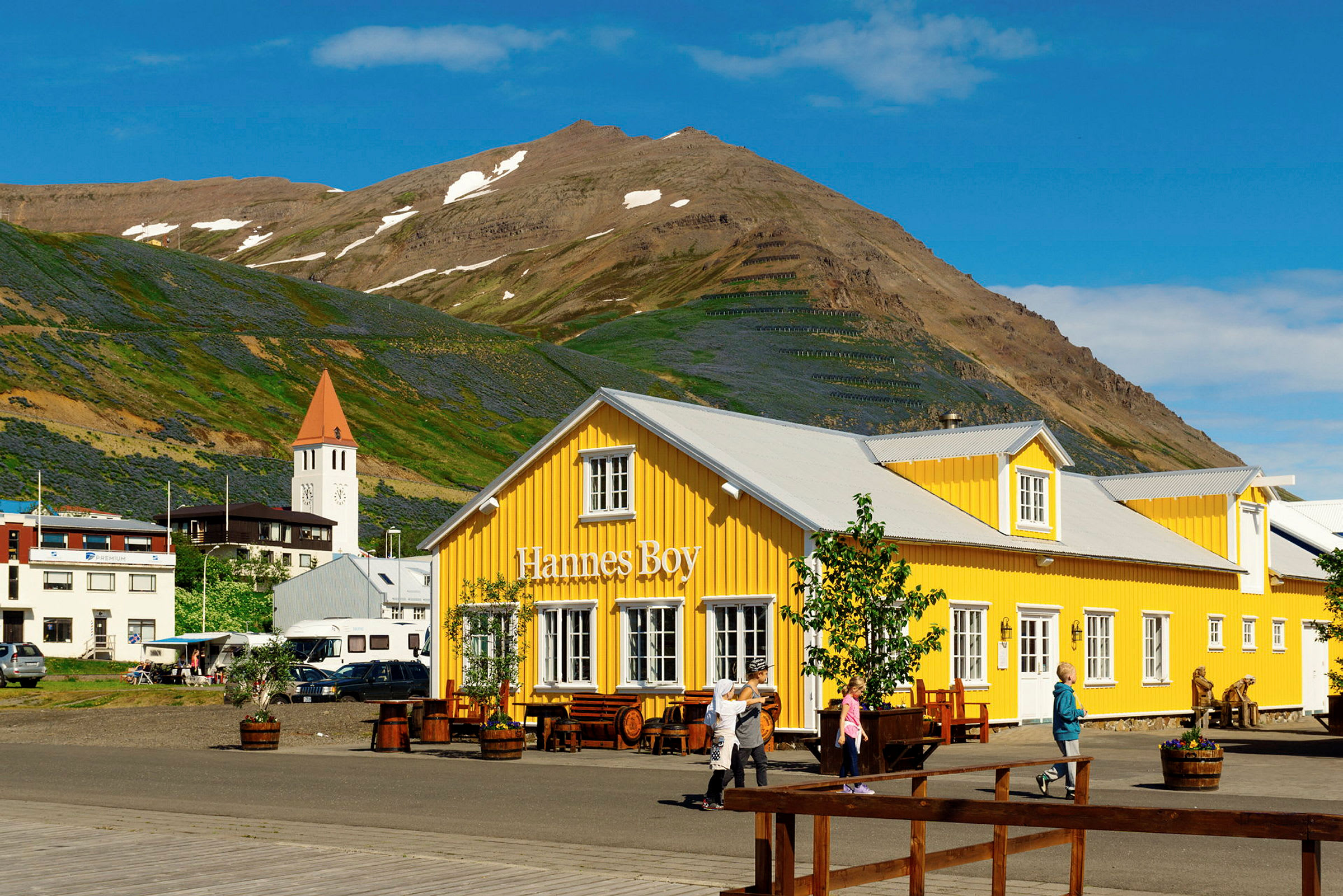 En gul byggnad med skylten "Hannes Boy" framför ett berg. (AI-genererad text)