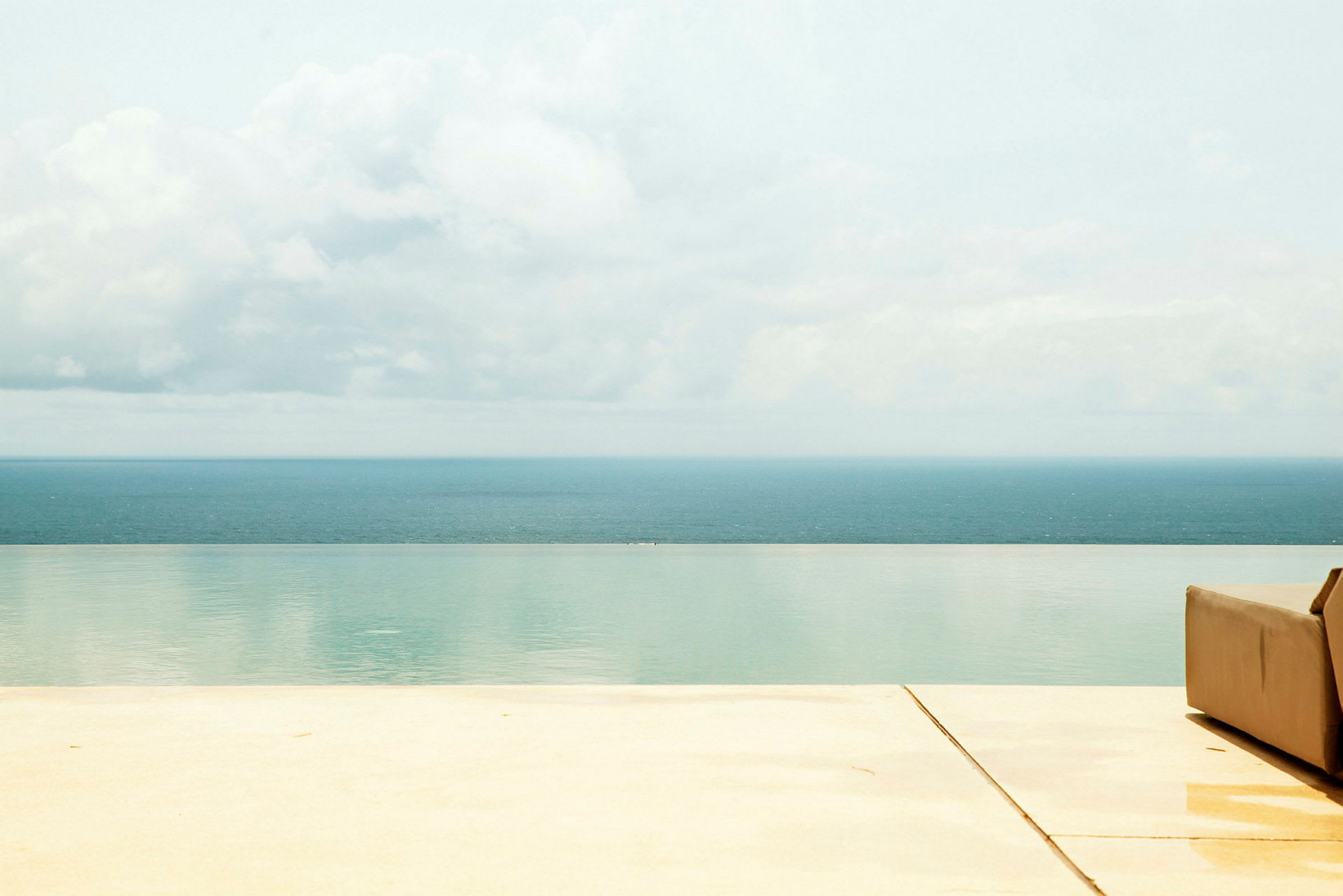 Bild av havsutsikt med infinitypool och en solstol vid poolkanten. (AI-genererad text)