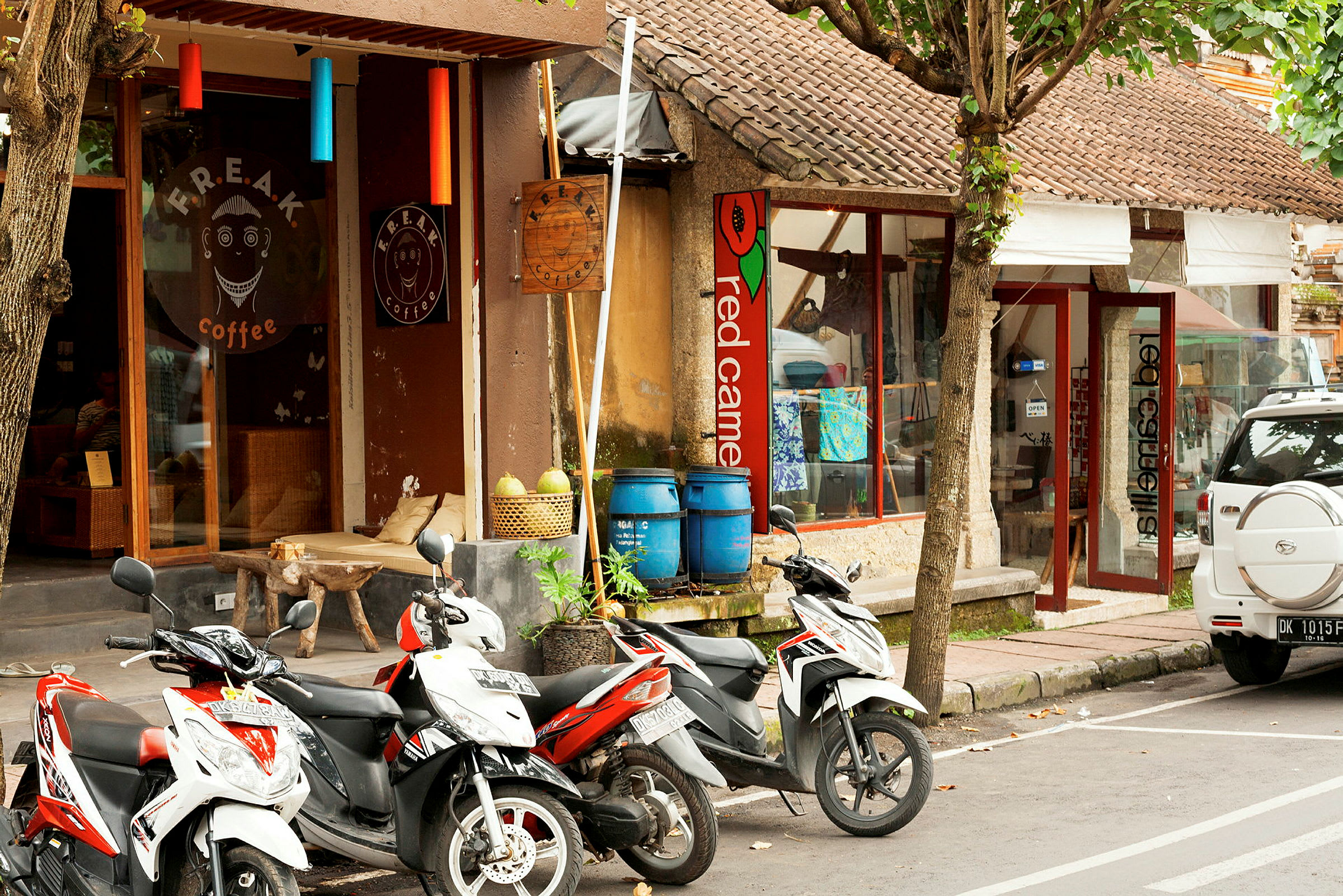 En gata med parkerade motorcyklar framför café och butiker. (AI-genererad text)