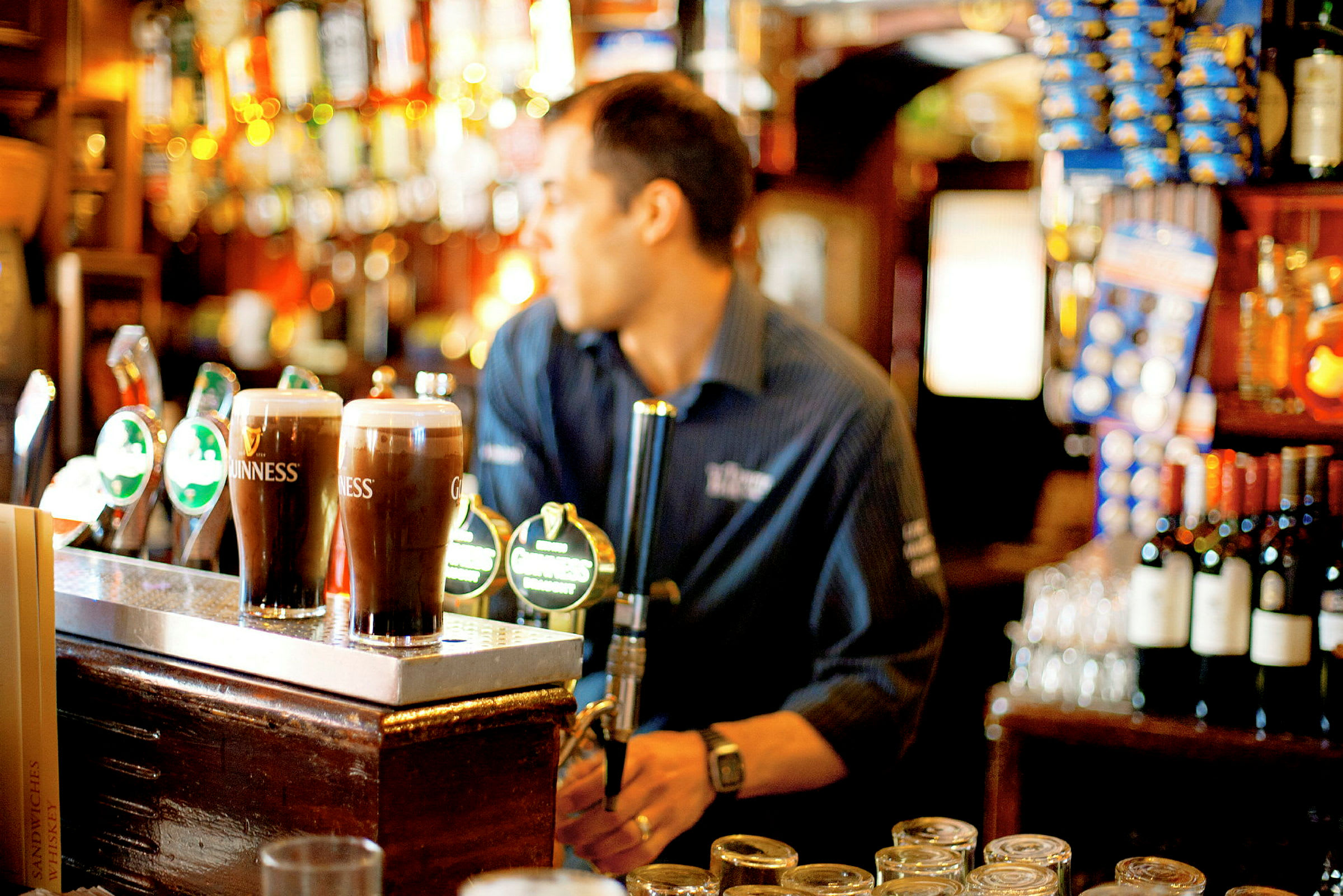 Bar med tappar för öl och flaskor i bakgrunden. (AI-genererad text)