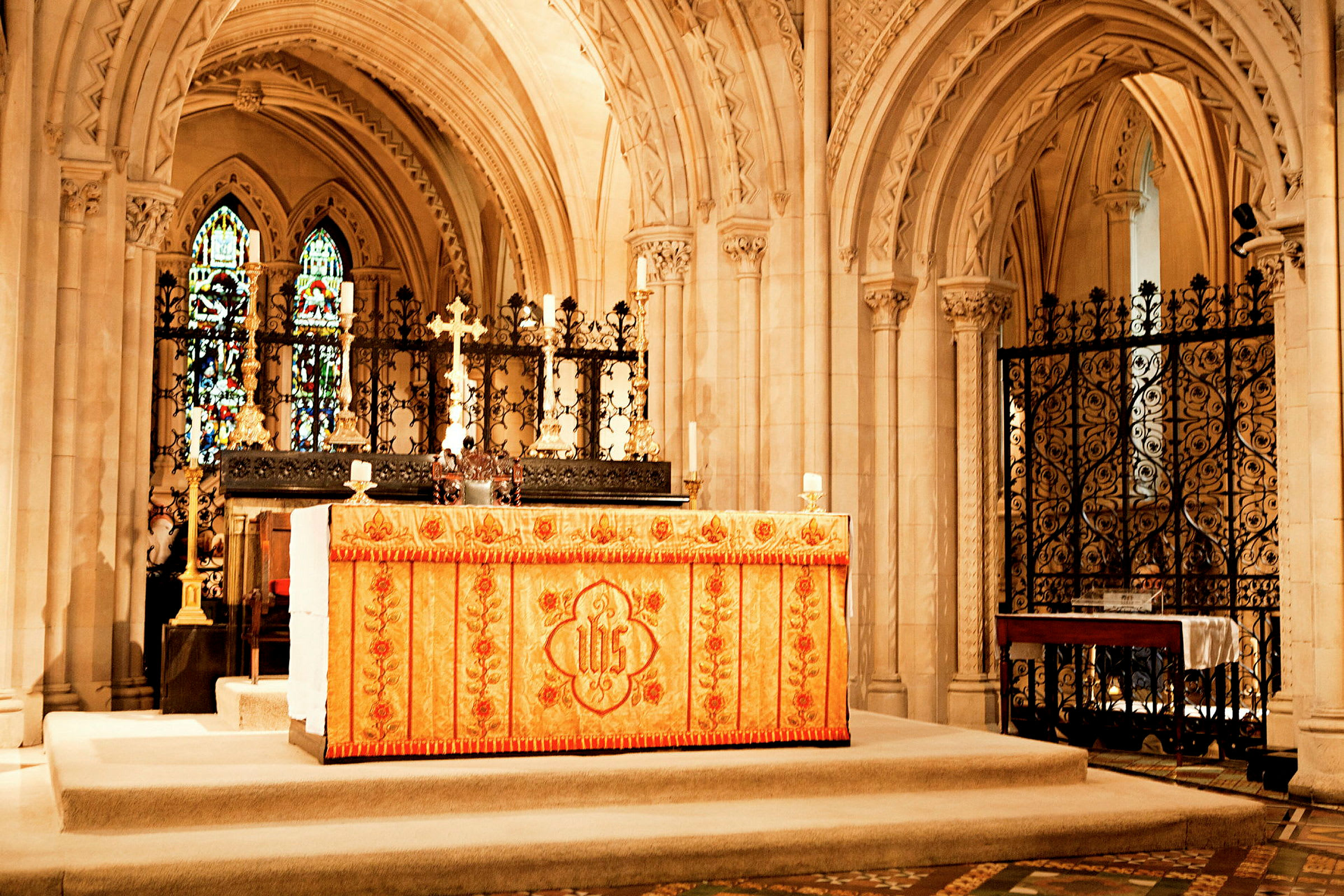 Ett altare i en kyrka med dekorerat tyg, kors och stearinljus. (AI-genererad text)