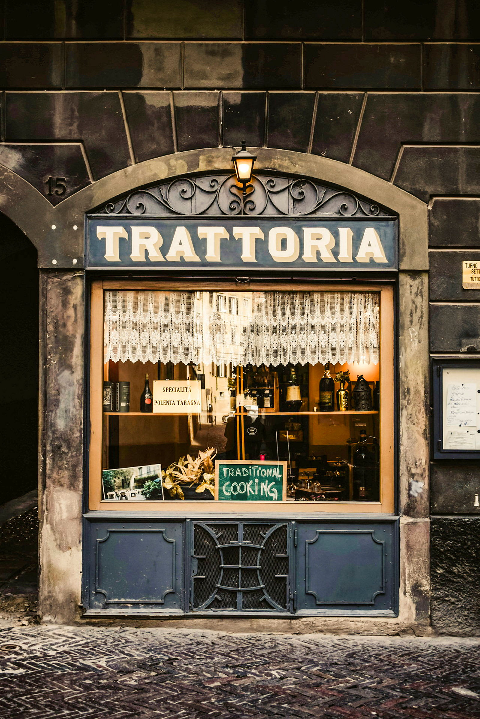 Ett skyltfönster till en trattoria med ett skylt som skriver 'Traditional Cooking' och en dukningsdekor. (AI-genererad text)