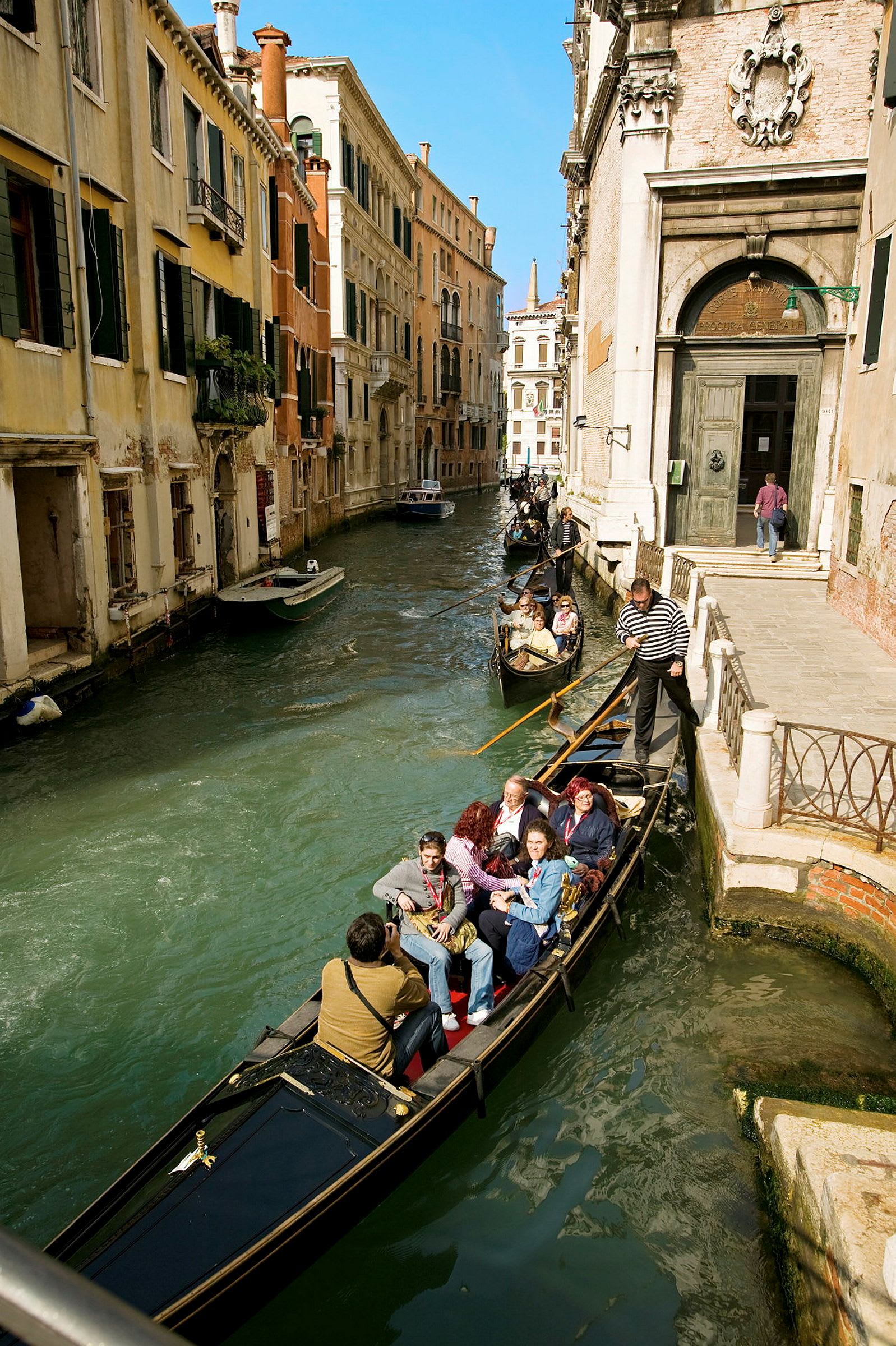 En gondol med passagerare färdas längs en kanal i Venedig. (AI-genererad text)