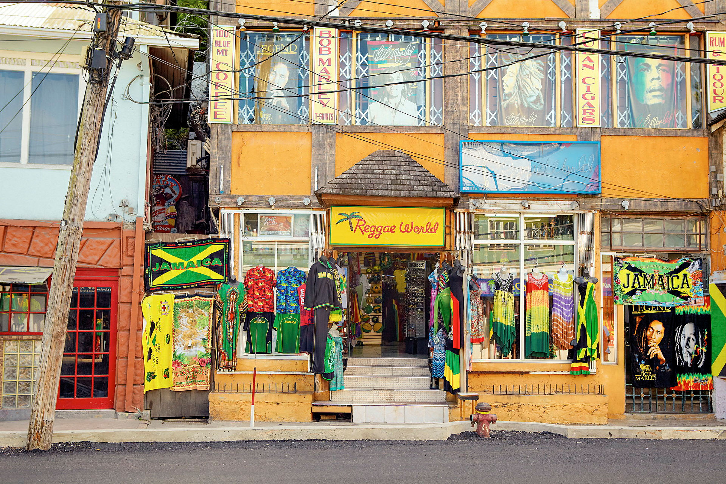 En färgstark butik med Reggae-tema ligger vid en gata, med kläder och skyltar inspirerade av Jamaica. (AI-genererad text)