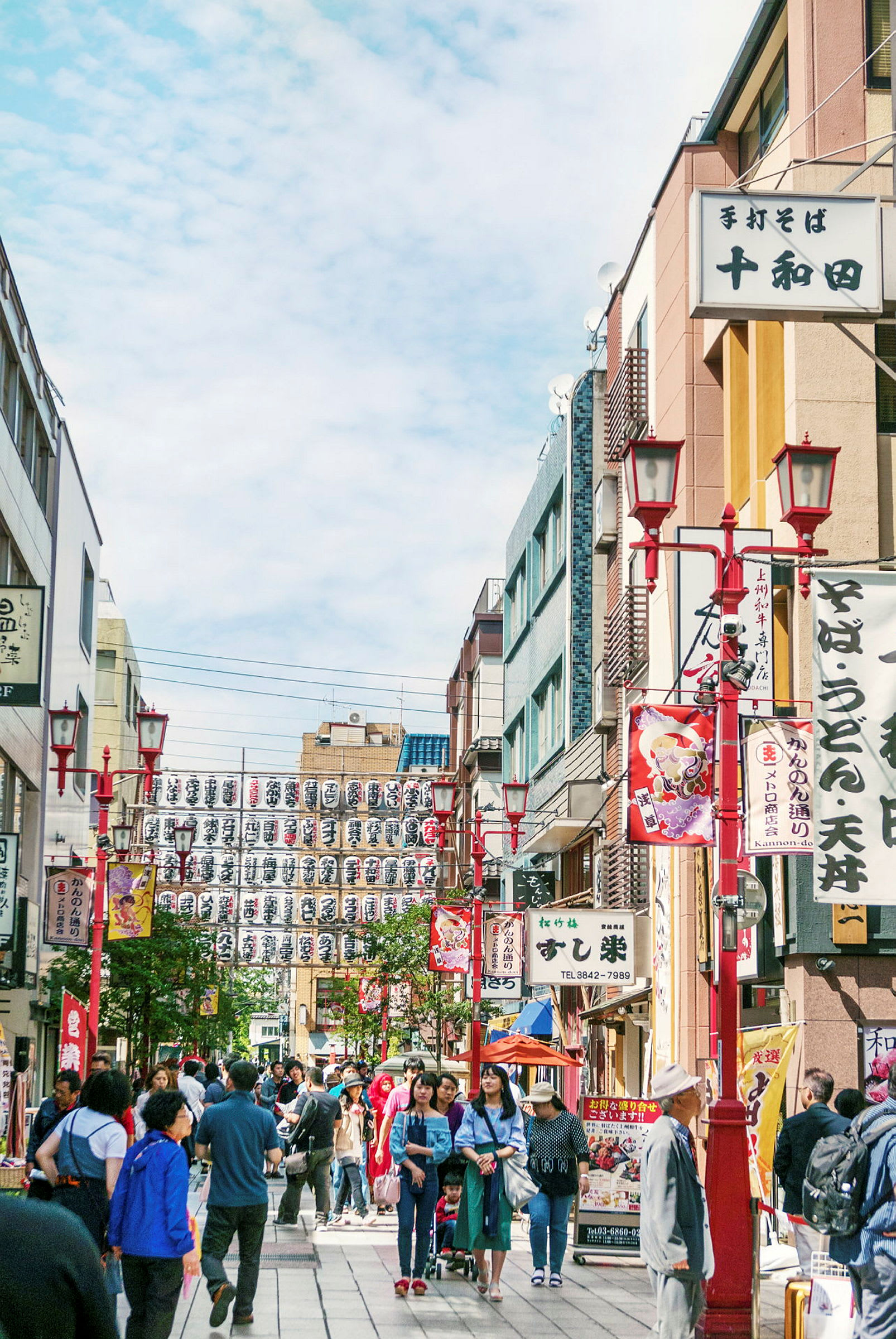 Ett livligt stadsområde med människor som promenerar på gatan omgivna av byggnader och japanska skyltar. (AI-genererad text)