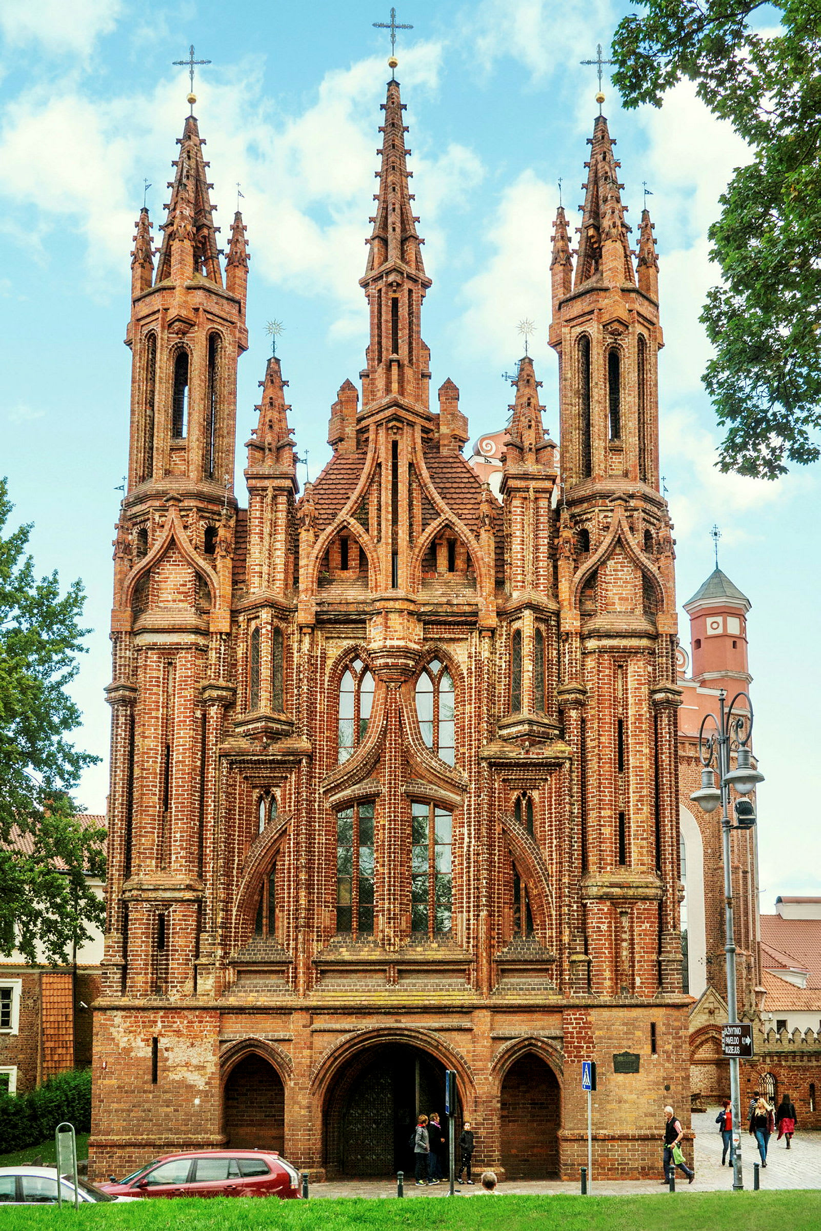 En gotisk kyrka i tegel med höga spiror och vackra fönster detaljer. (AI-genererad text)