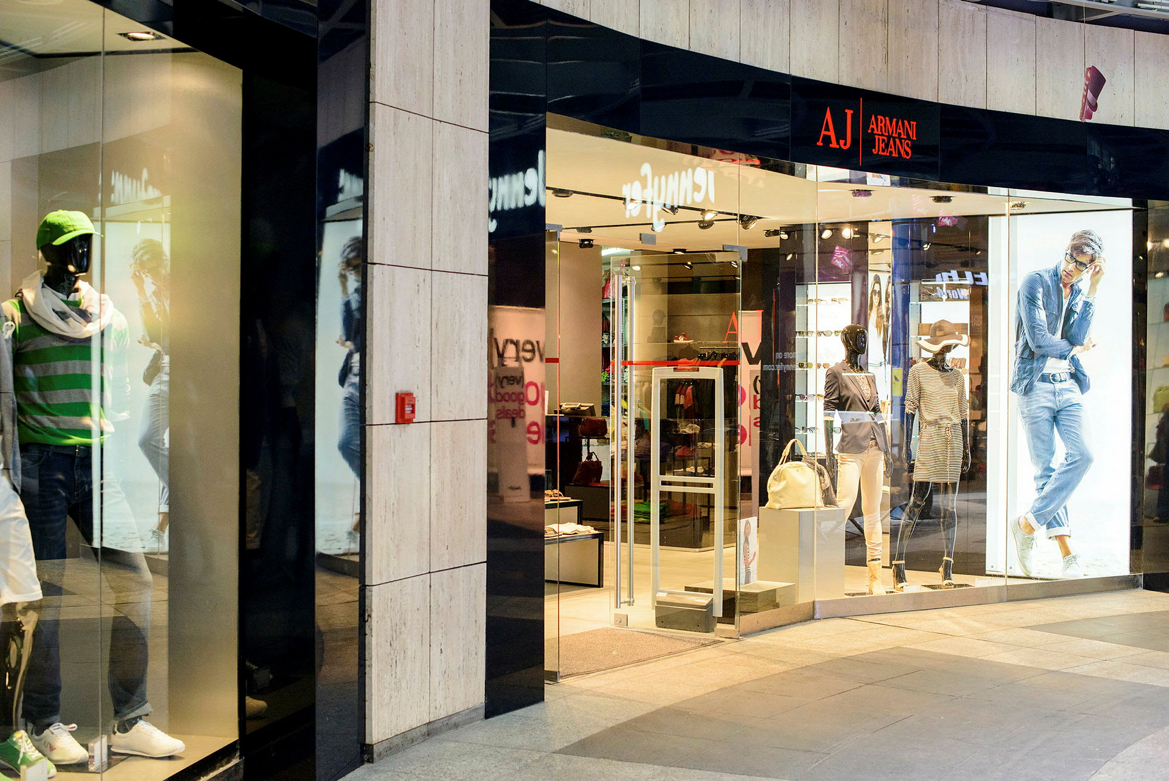 En butik med modekläder, skyltdockor i skyltfönstret och en öppning som visar varor inuti. (AI-genererad text)