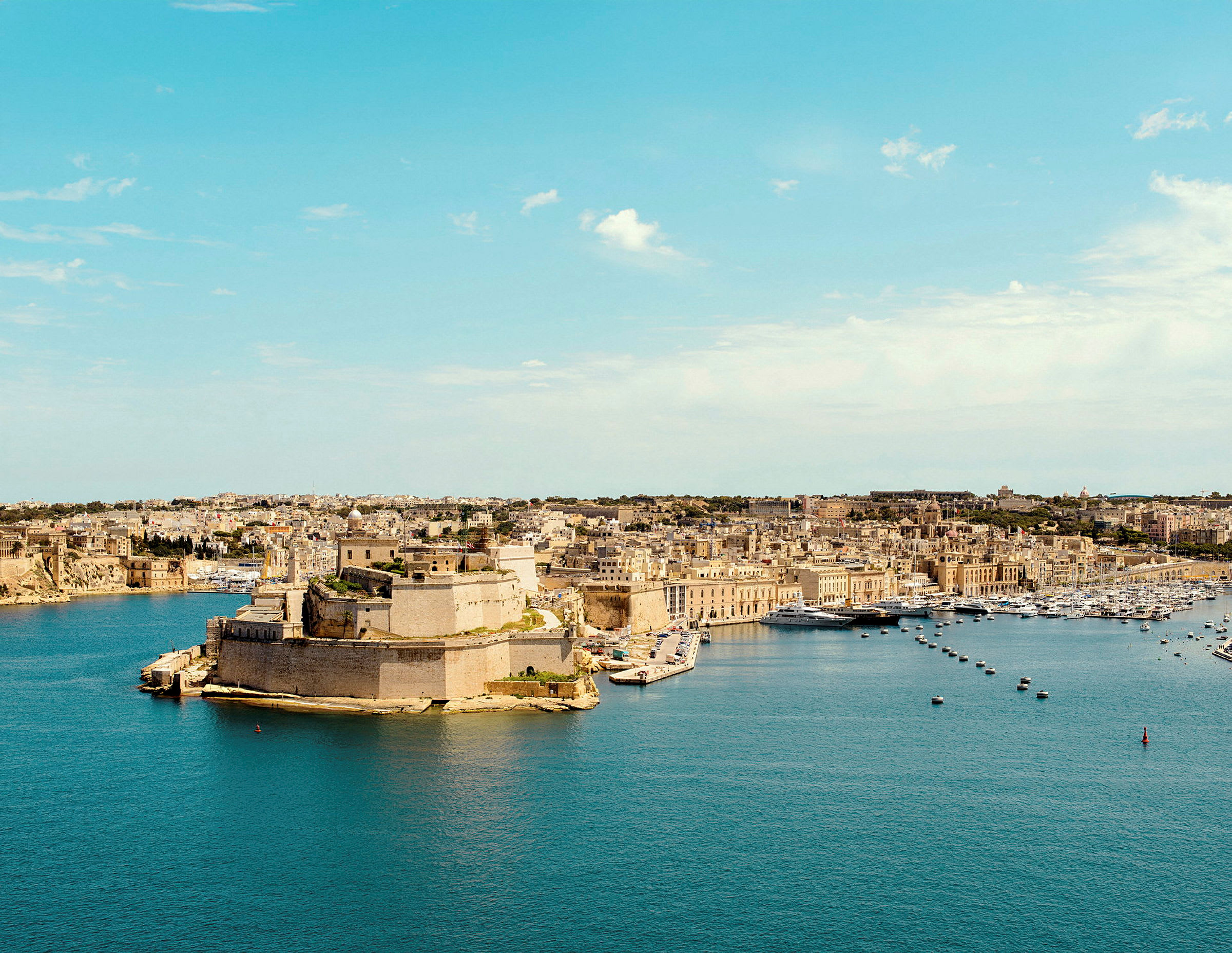 Vy över en kuststad med historiska byggnader och hamn. (AI-genererad text)