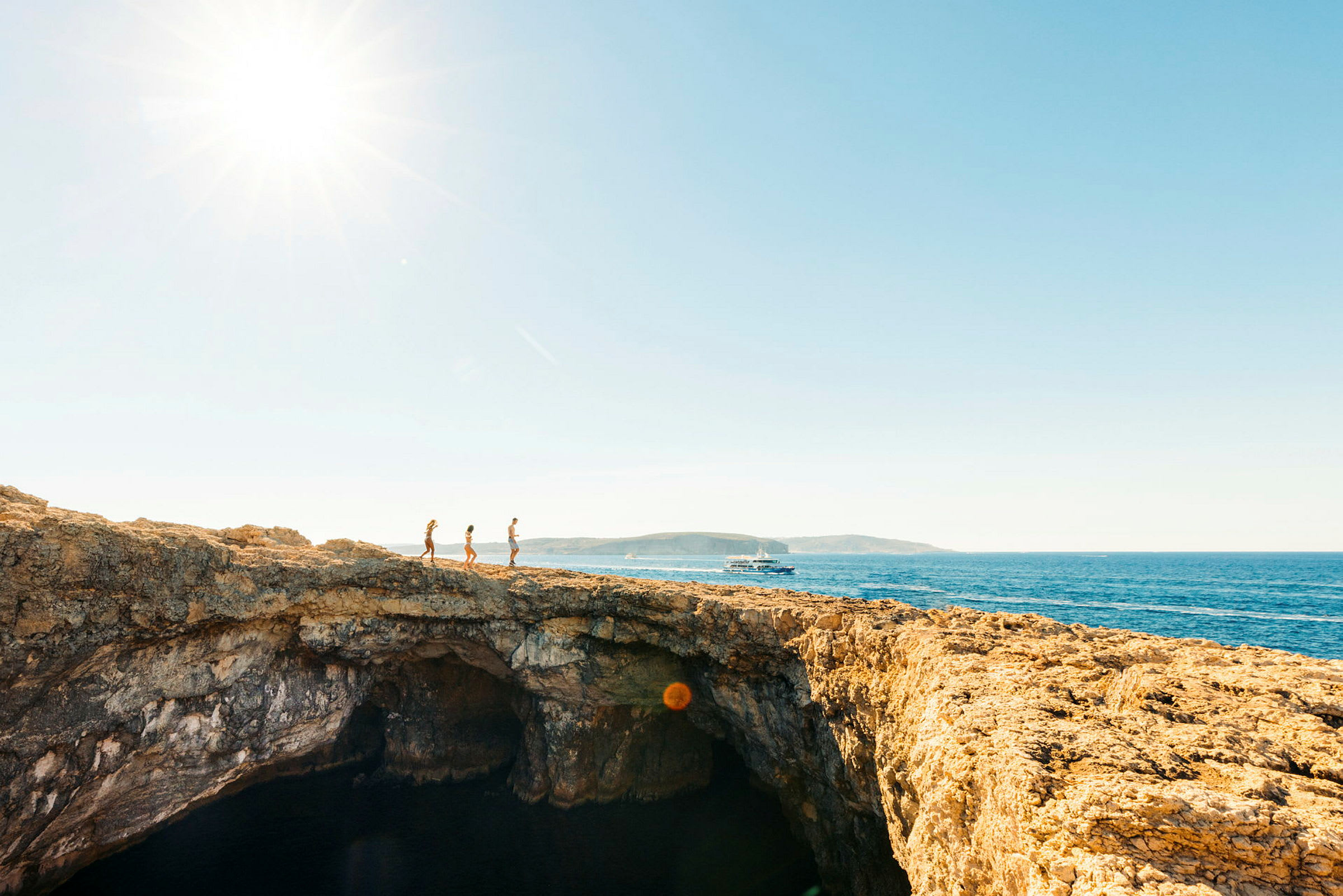 Tre personer går på en klippa med havet i bakgrunden. (AI-genererad text)