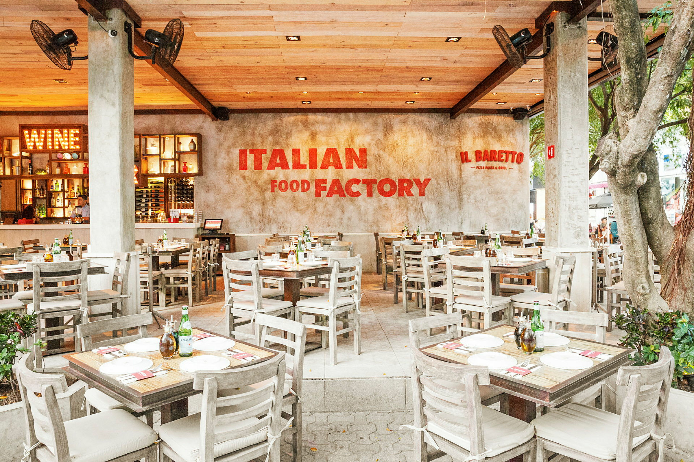 En italiensk restaurang med träbord och stolar, en välkomnande atmosfär och en skylt med texten "Italian Food Factory" på väggen. (AI-genererad text)