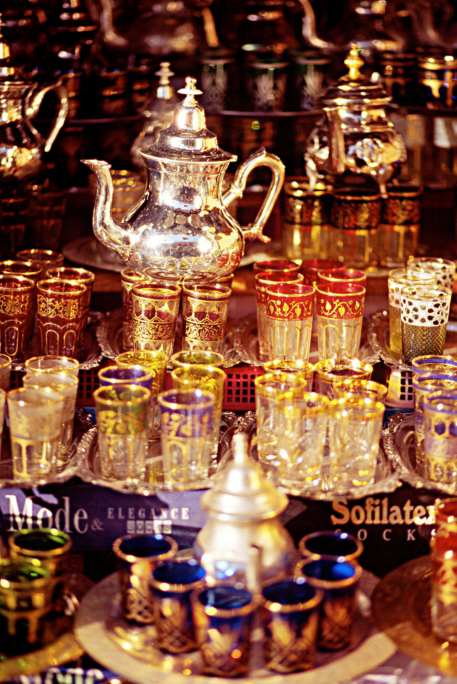 En samling av dekorativa tekannor och färgglada glas med detaljerad ornamentering. (AI-genererad text)