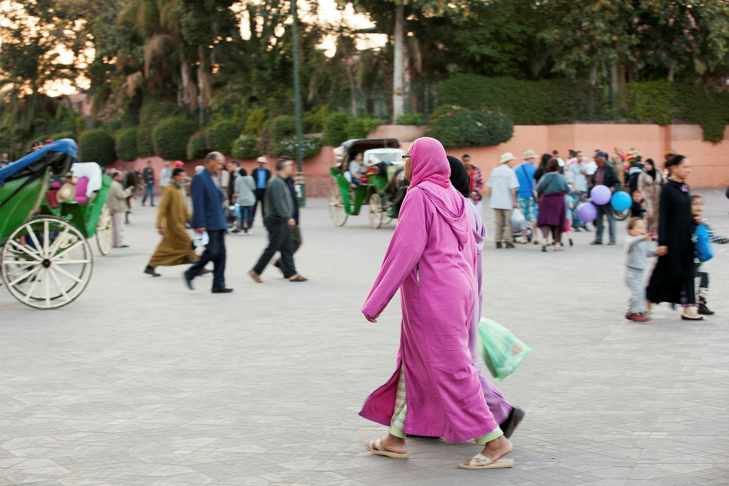 Personer promenerar på ett torg med en grön vagn i bakgrunden. (AI-genererad text)