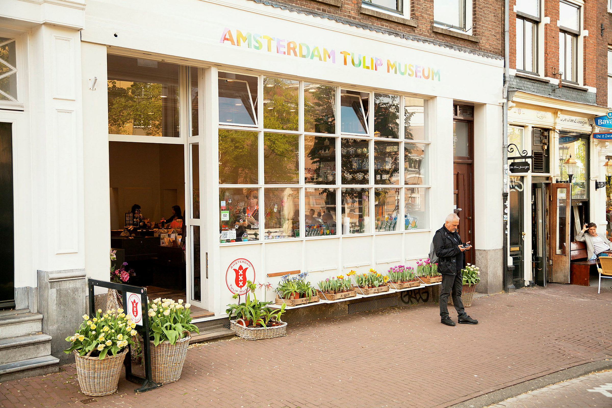 Entrén till Amsterdam Tulip Museum, med blommor framför och människor inne i butiken. (AI-genererad text)