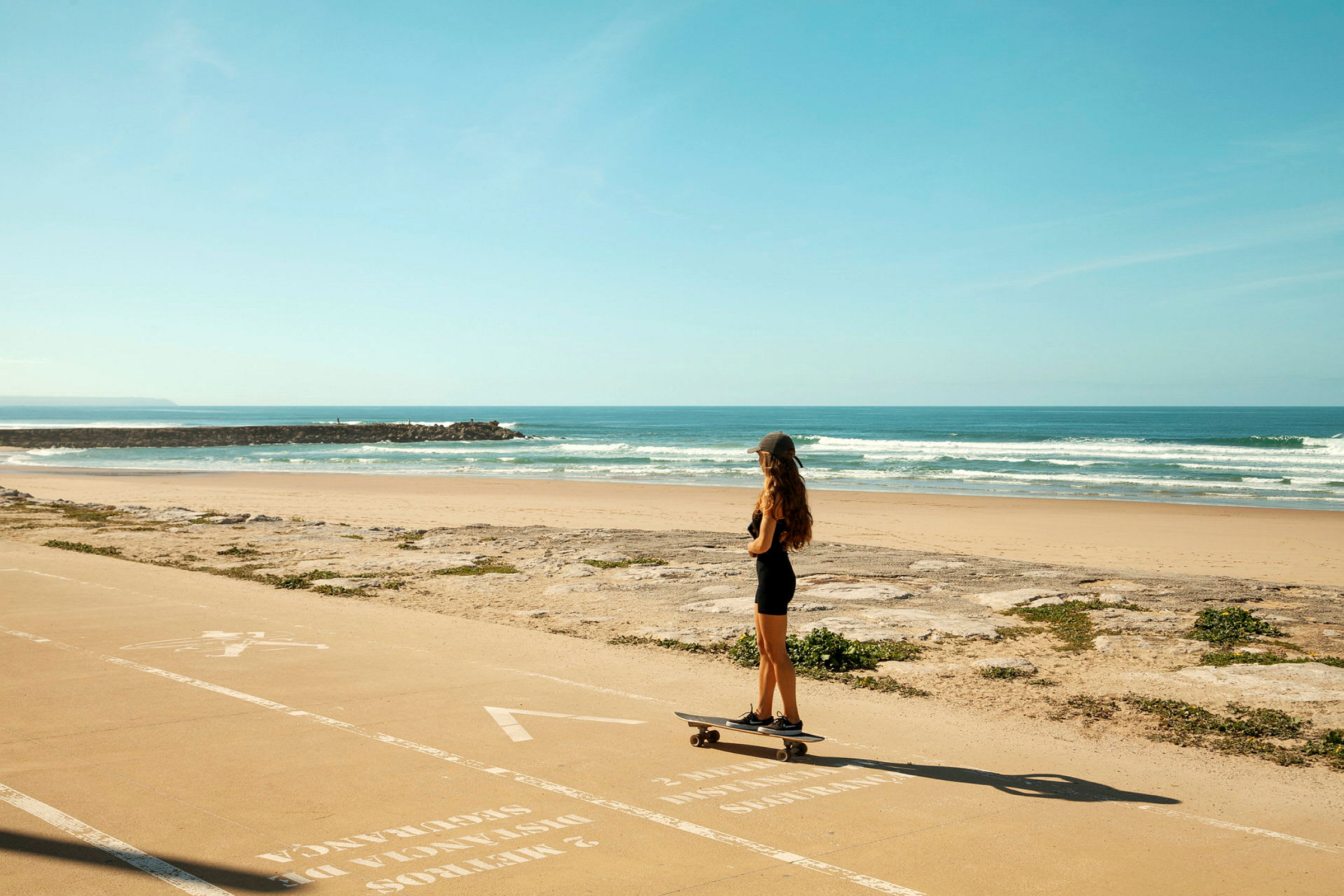 En person åker skateboard på en gångväg vid stranden. (AI-genererad text)
