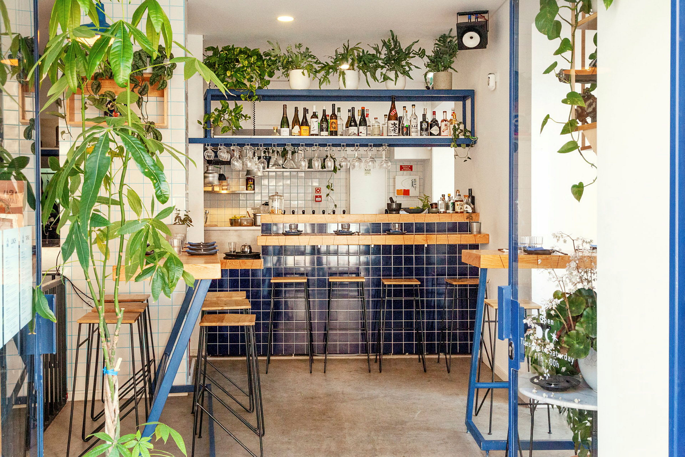 En modern bar med blå kakel, trädetaljer och grönska. (AI-genererad text)