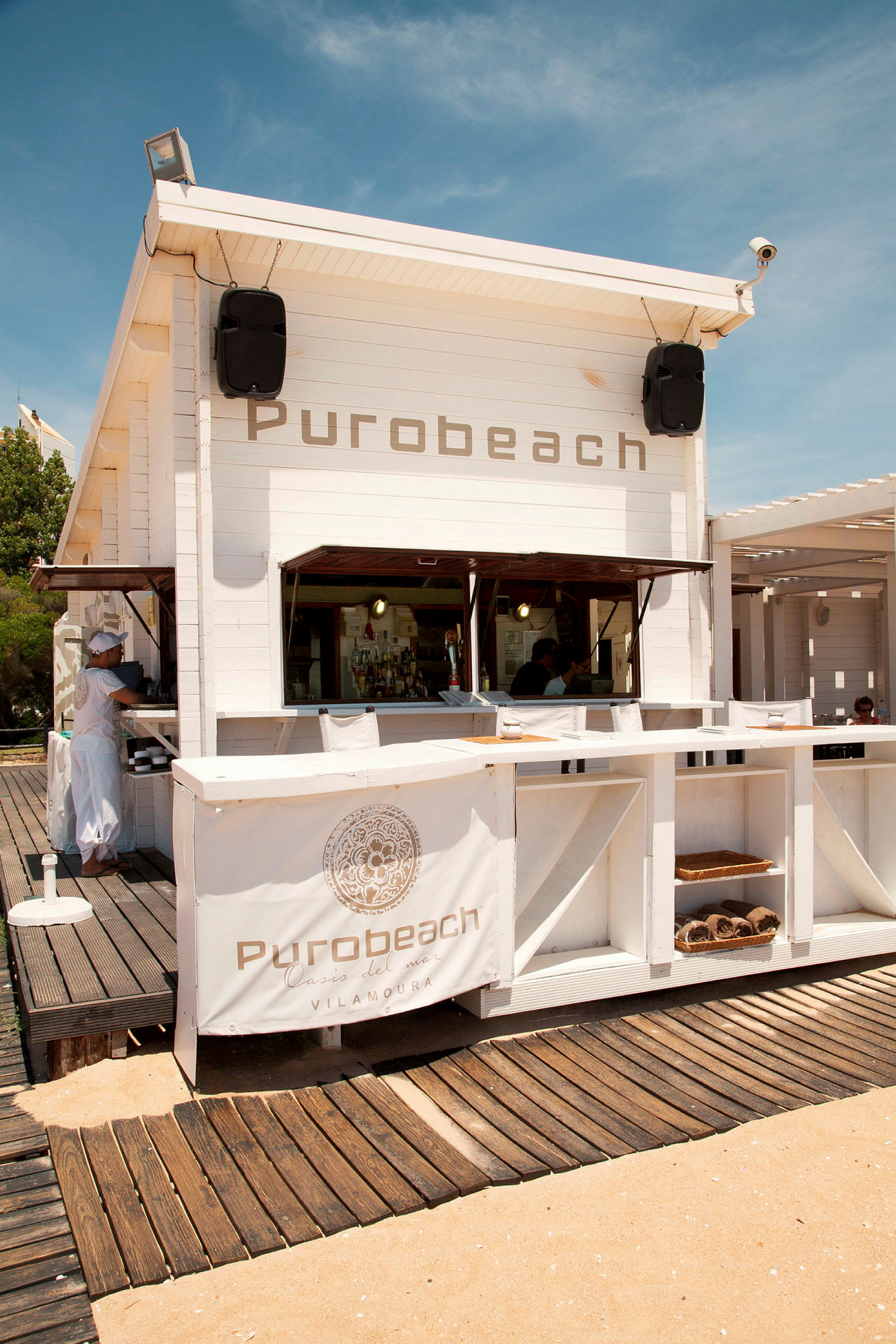 Vit träbyggnad med texten 'Purobeach' på dess framsida. (AI-genererad text)