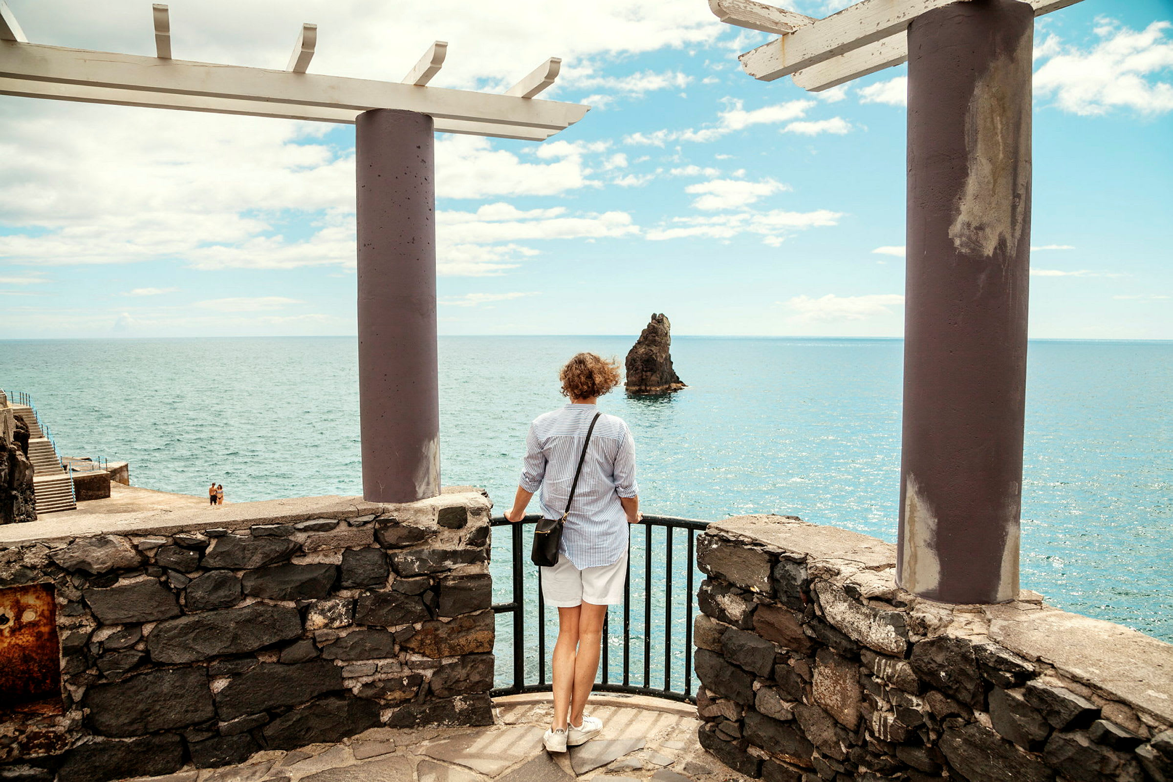 En person står på en stenplattform och tittar på en klippa i havet. (AI-genererad text)