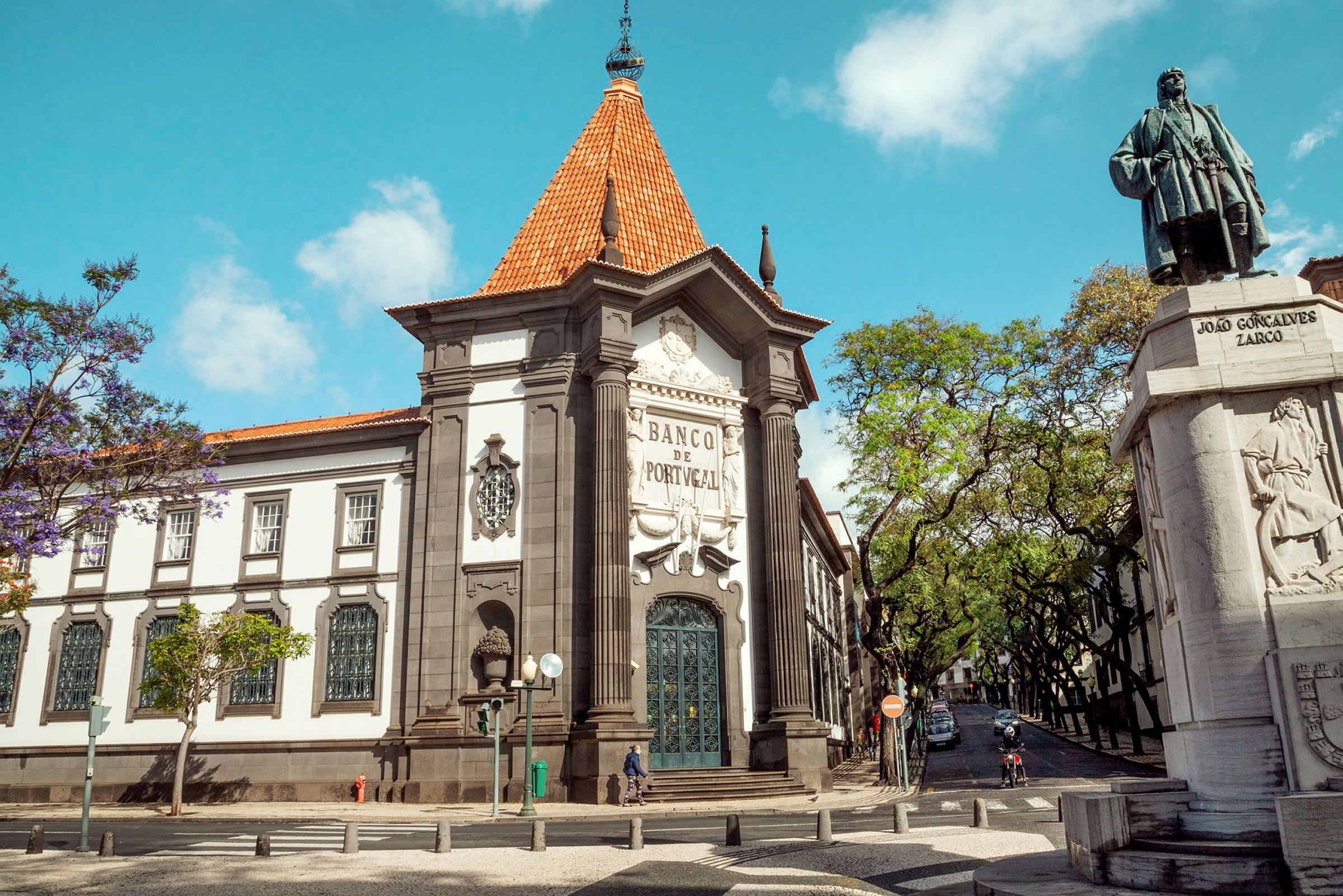 Byggnaden för Banco de Portugal med en staty av João Gonçalves Zarco i förgrunden. (AI-genererad text)