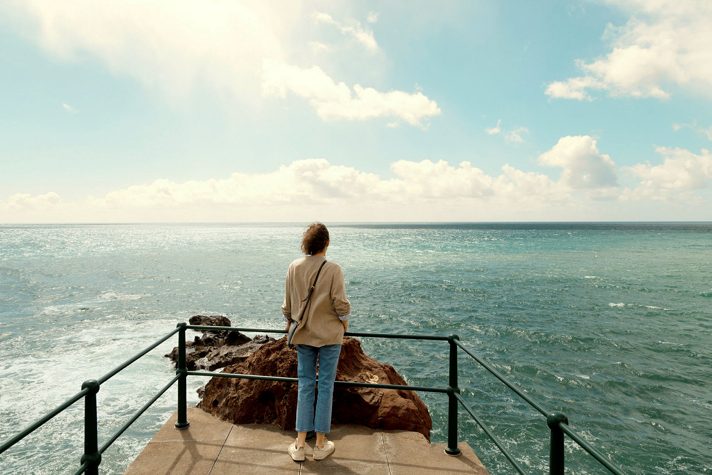 En person står på en utsiktsplats och blickar ut över havet. (AI-genererad text)