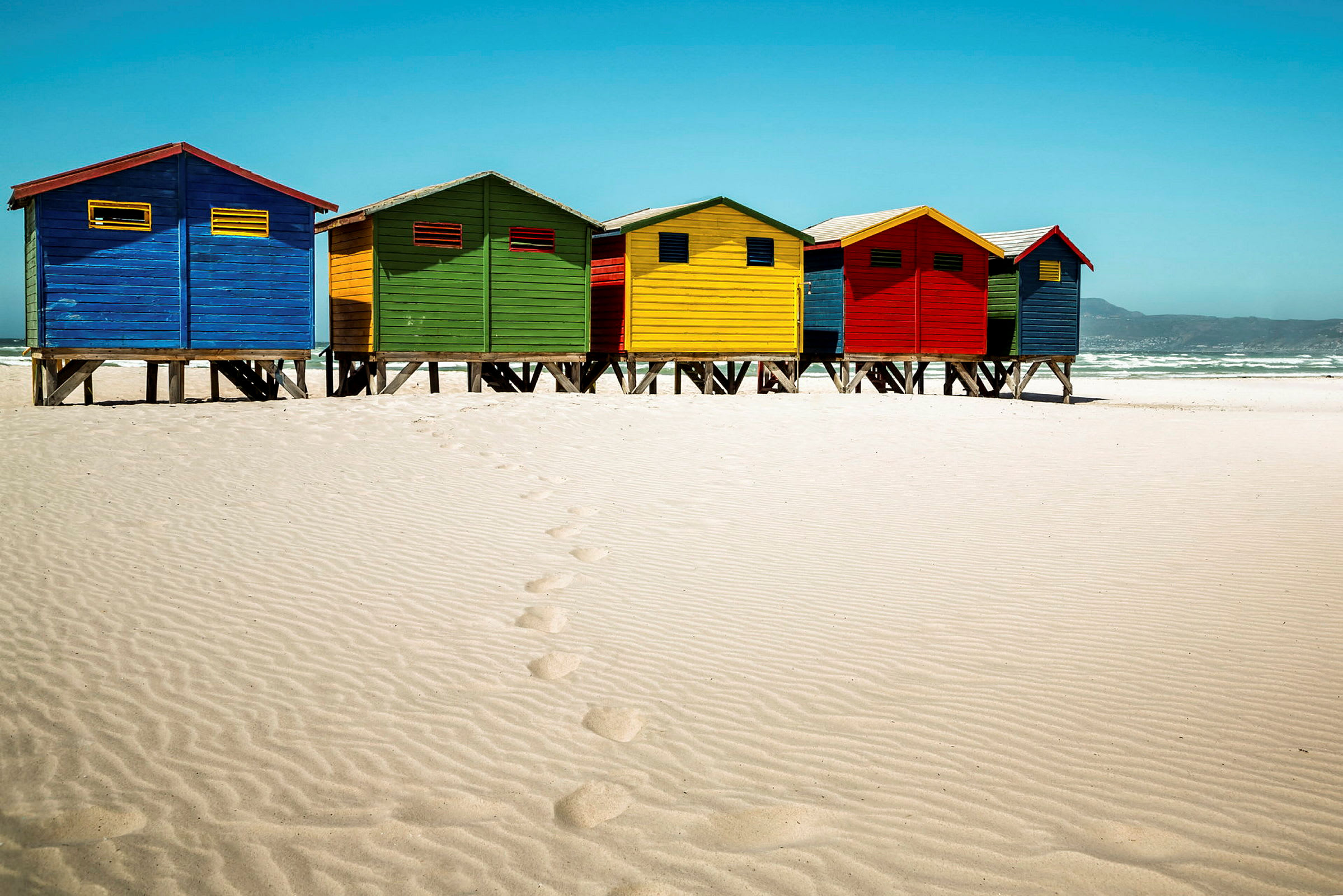 Färgglada strandstugor på en sandstrand. (AI-genererad text)