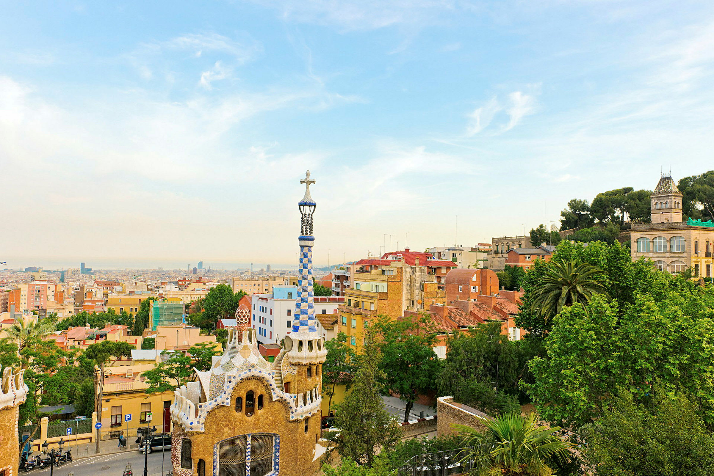 Vy över Park Güell i Barcelona med färgglada byggnader och stadens skyline i bakgrunden. (AI-genererad text)