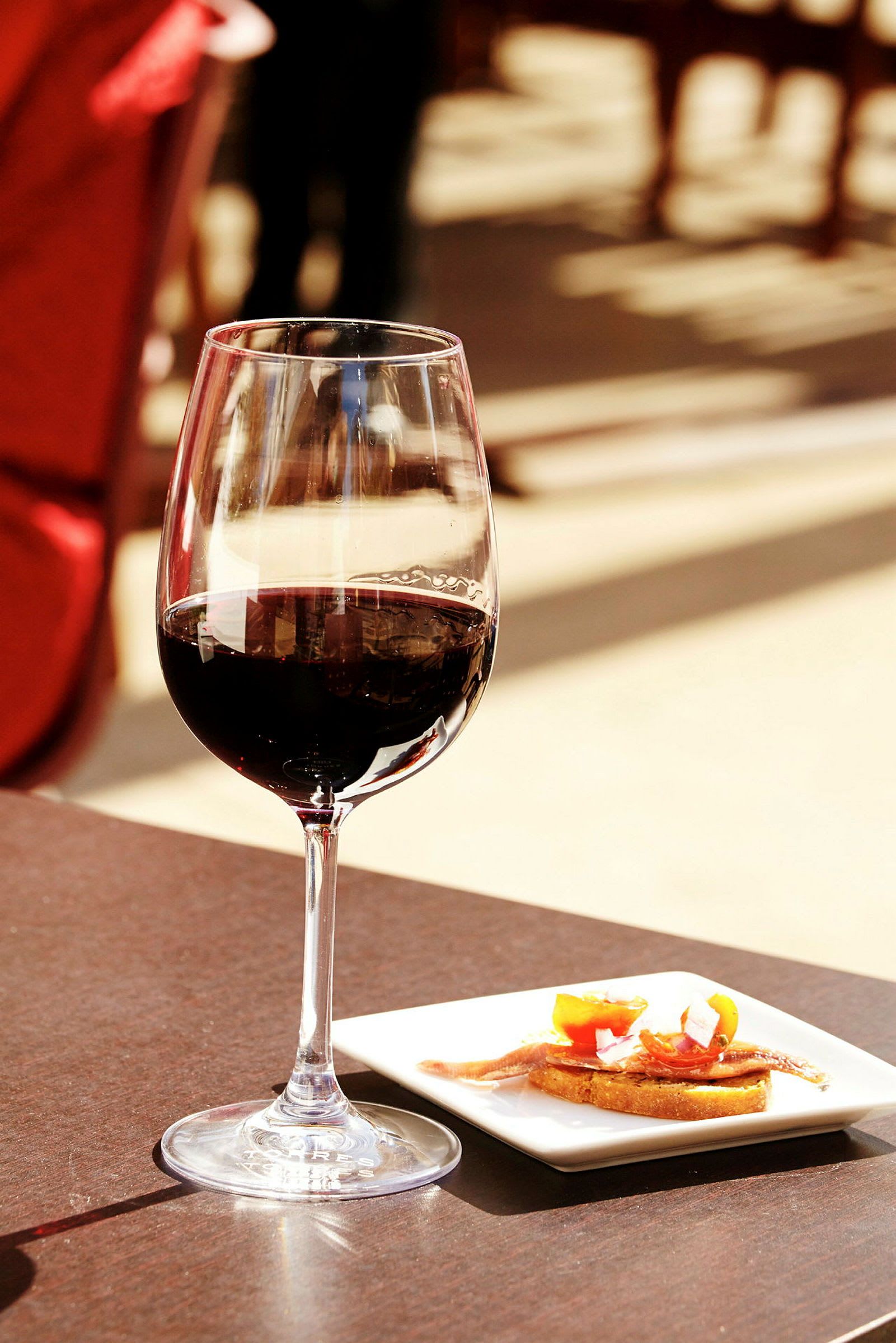 Ett glas rött vin och en tallrik med förrätt på ett bord. (AI-genererad text)