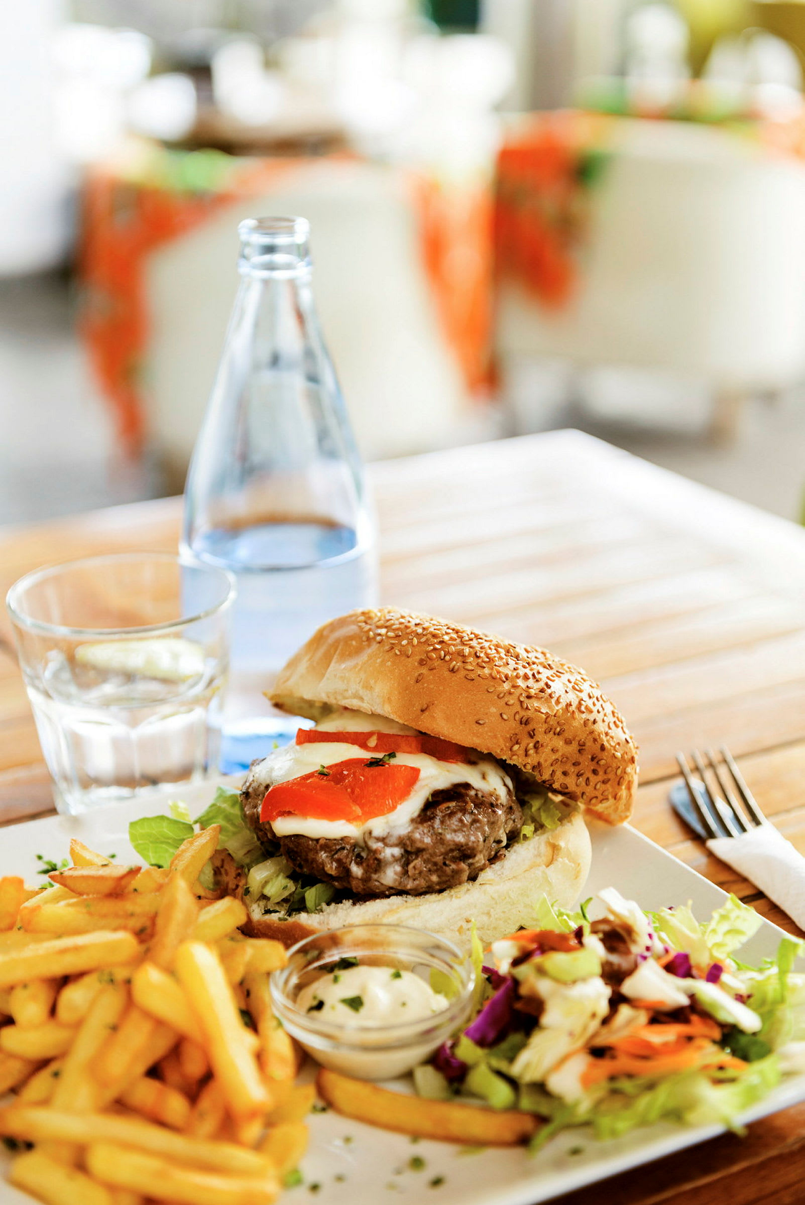 Tallrik med hamburgare, pommes frites, sallad och sås serverad på ett träbord. (AI-genererad text)