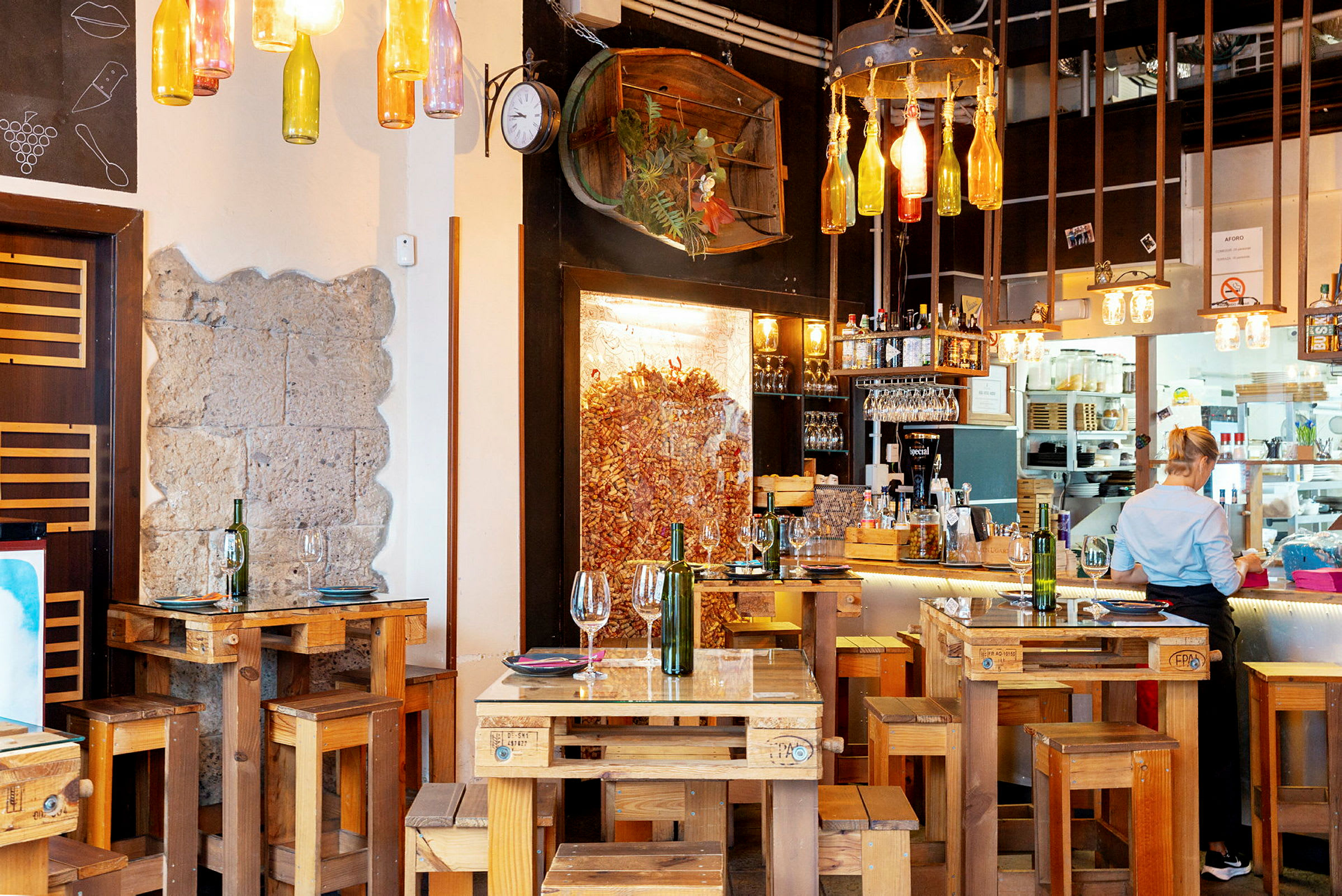Restaurang med rustika trämöbler och dekorativa flaskor hängande från taket. (AI-genererad text)