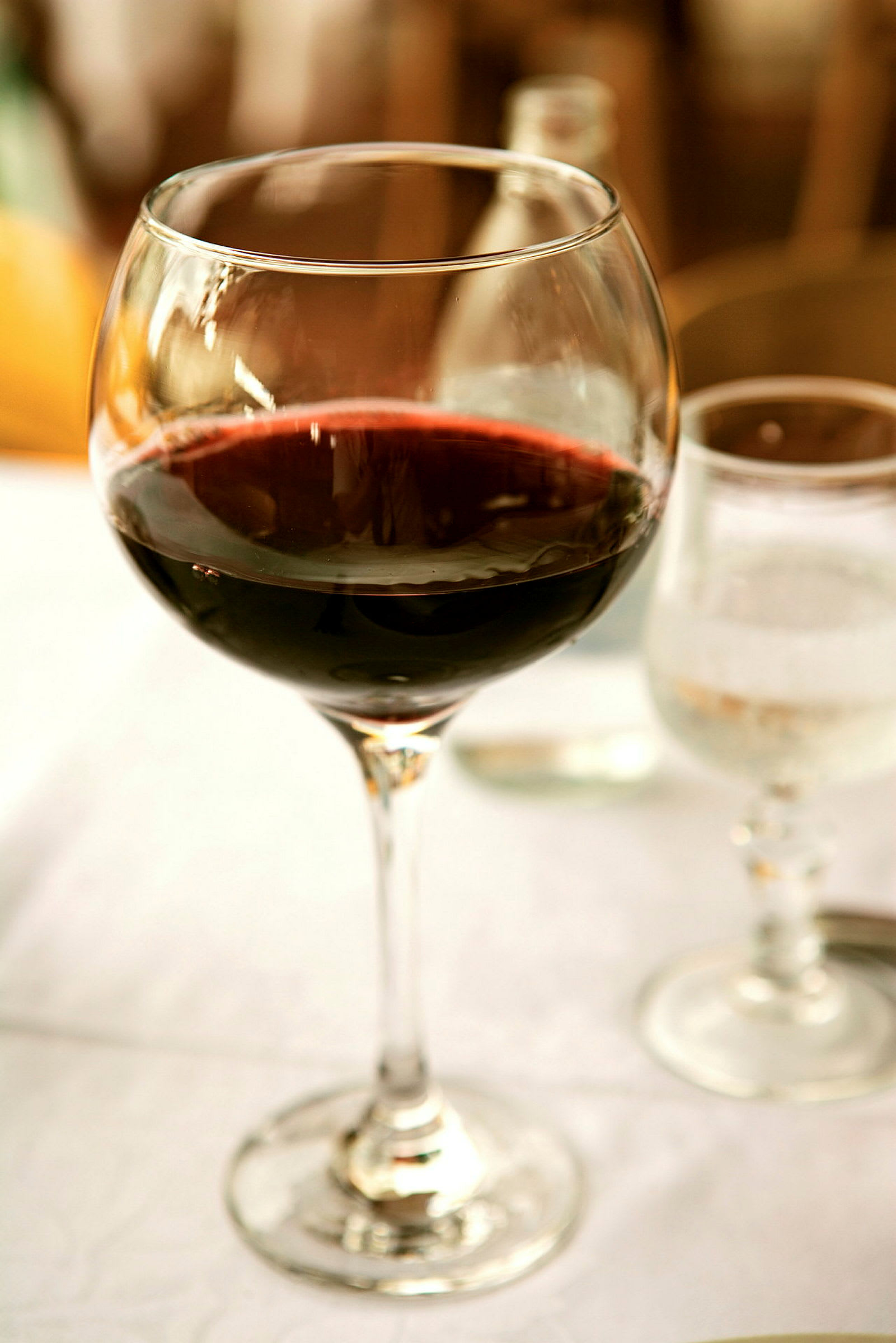 Ett vinglas med rött vin på ett dukat bord. (AI-genererad text)